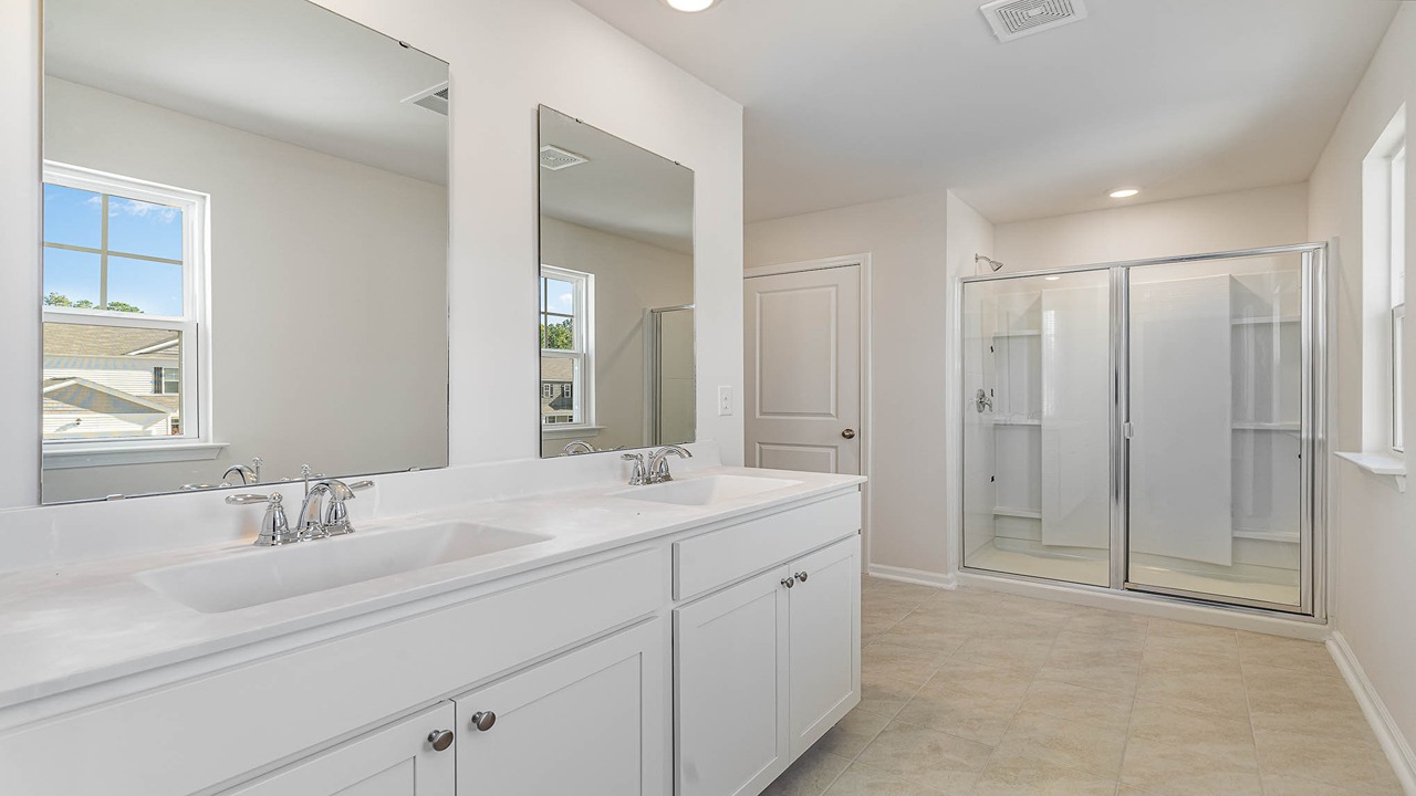 The primary bathroom features double sinks and a standup shower.