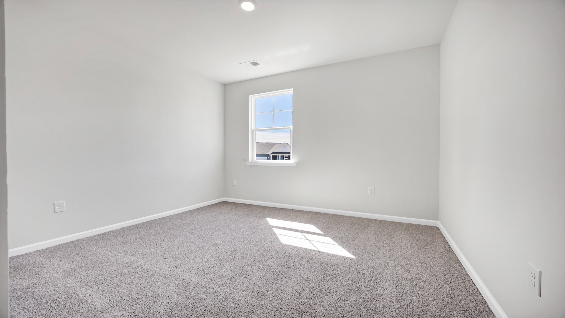 Downstairs bedroom in new construction home with a window for light and plush carpet floors