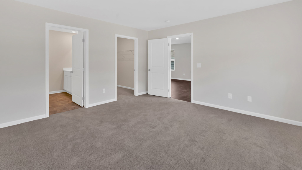 The primary bedroom features a large window and private primary bathrooms and closet.