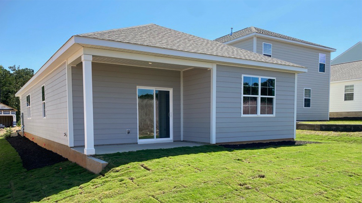 Back exterior of the home with a covered back patio and green grass.