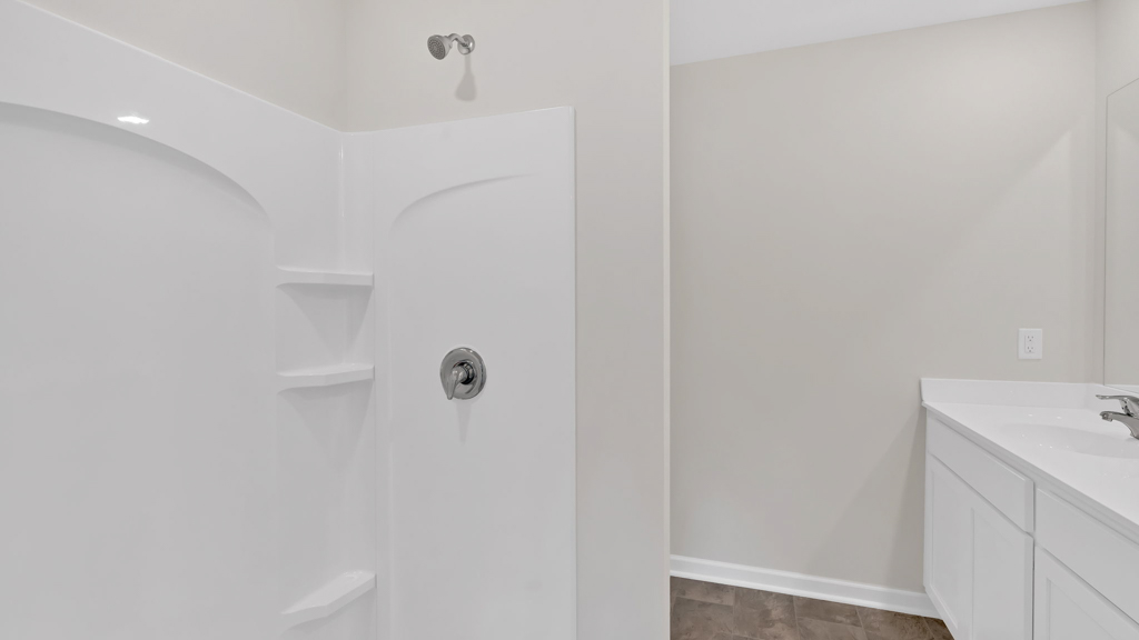 The primary bathroom features a double vanity, white cabinetry, and a standup shower.