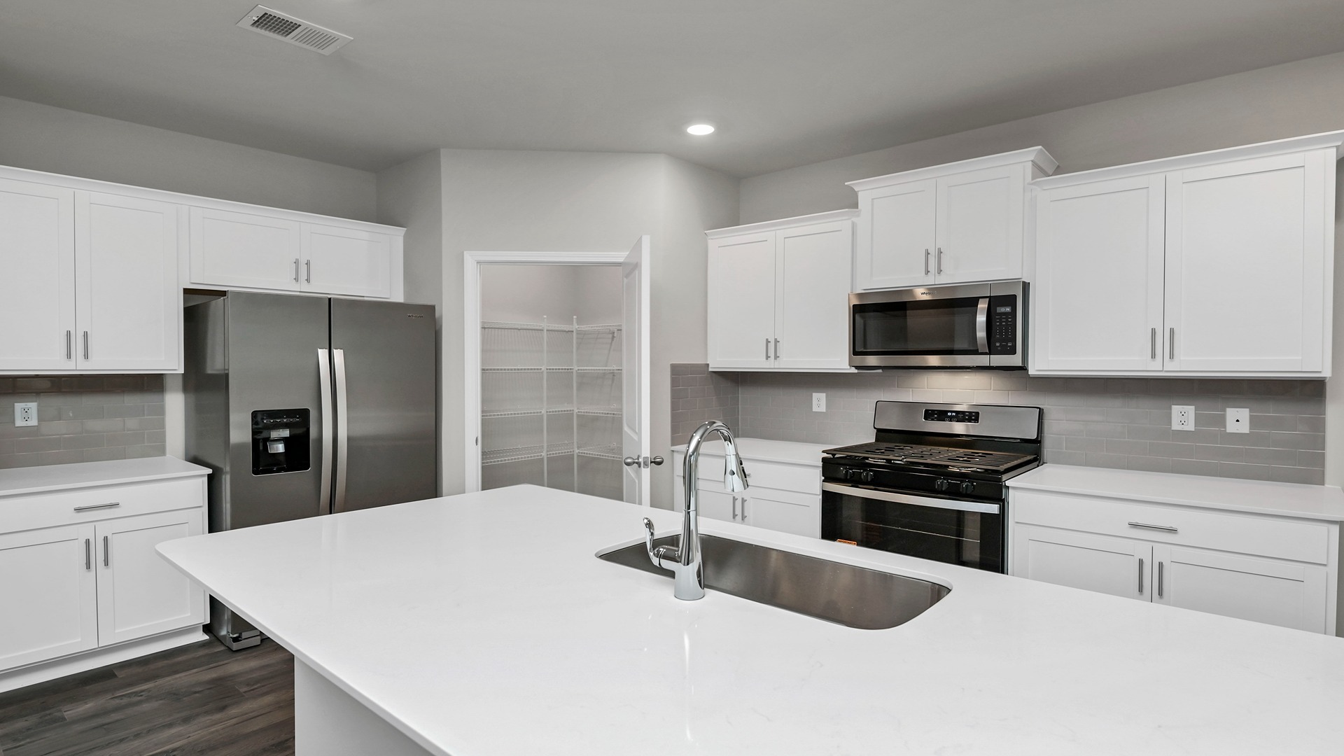 Modern white quartz countertops and tile backsplash in the kitchen space