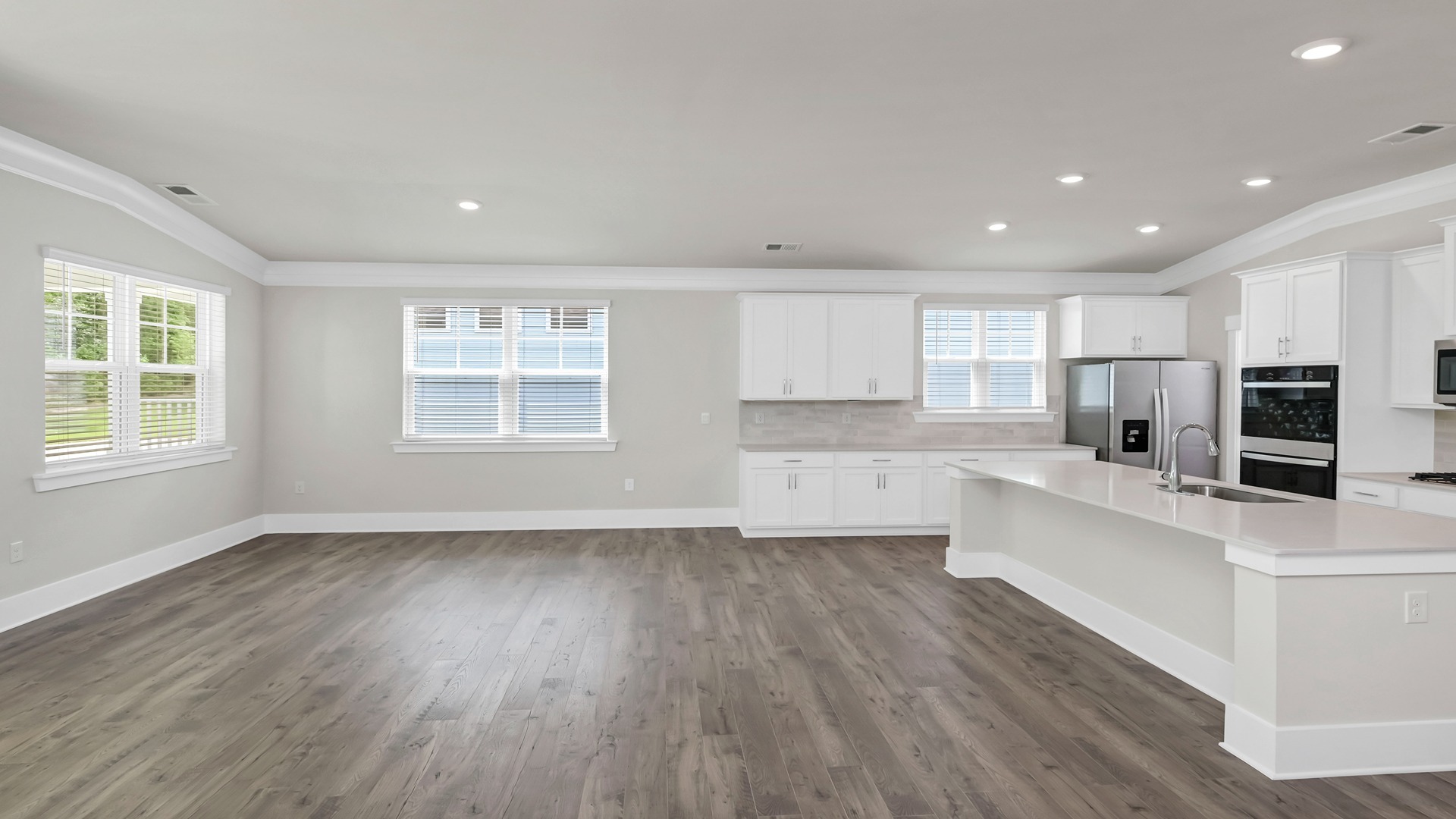 The kitchen and living areas are open with several windows and luxury flooring.
