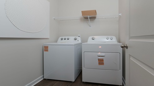 The laundry room features shelving above and vinyl flooring.