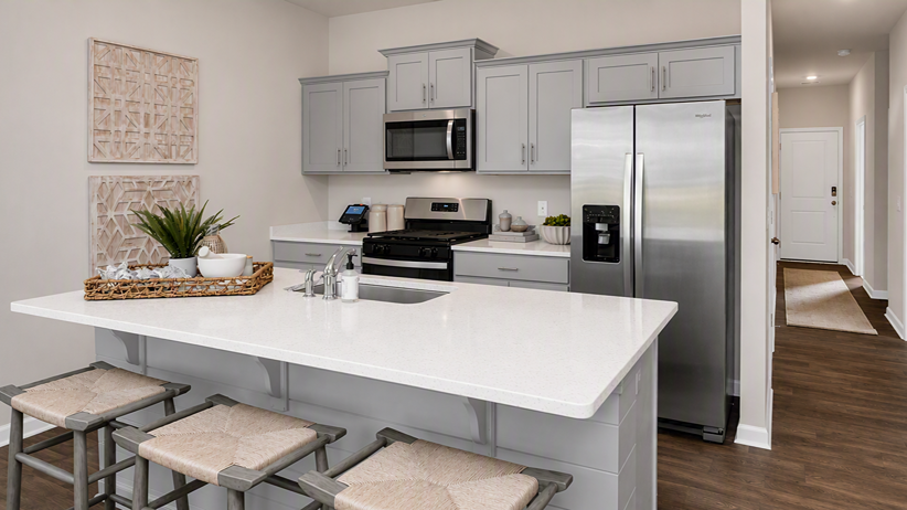 Modern kitchen area in the Devon floor plan with gray cabinets and white quartz countertops