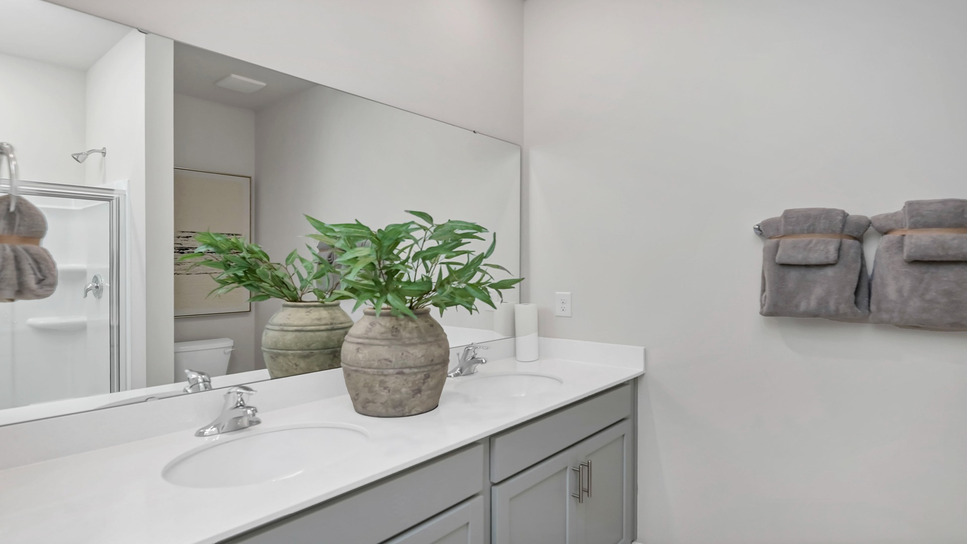 Primary bathroom with double vanity and gray cabinetry