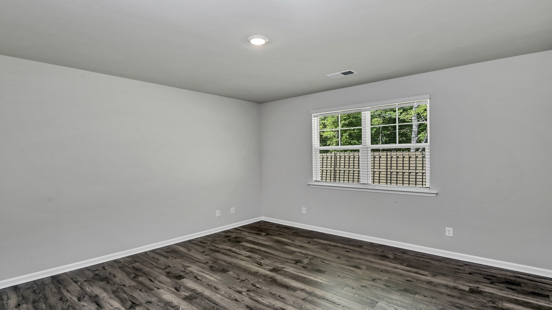 Primary bedroom at the back of the home with a large window facing the backyard