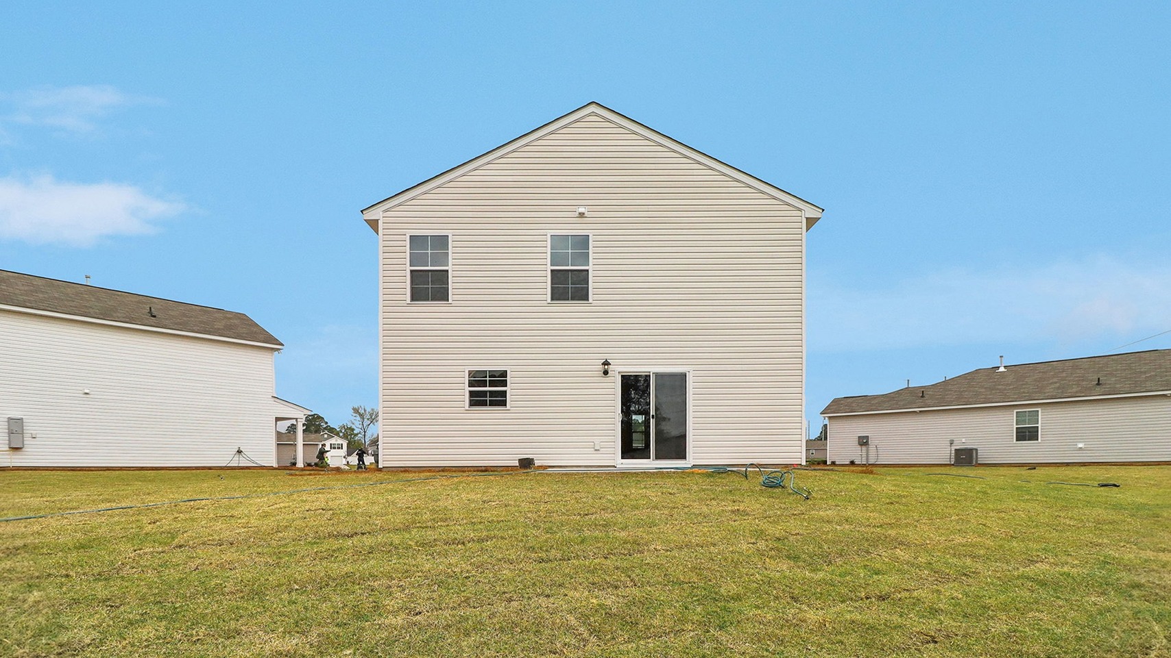 Back exterior of the home featuring a spacious yard and paved back patio