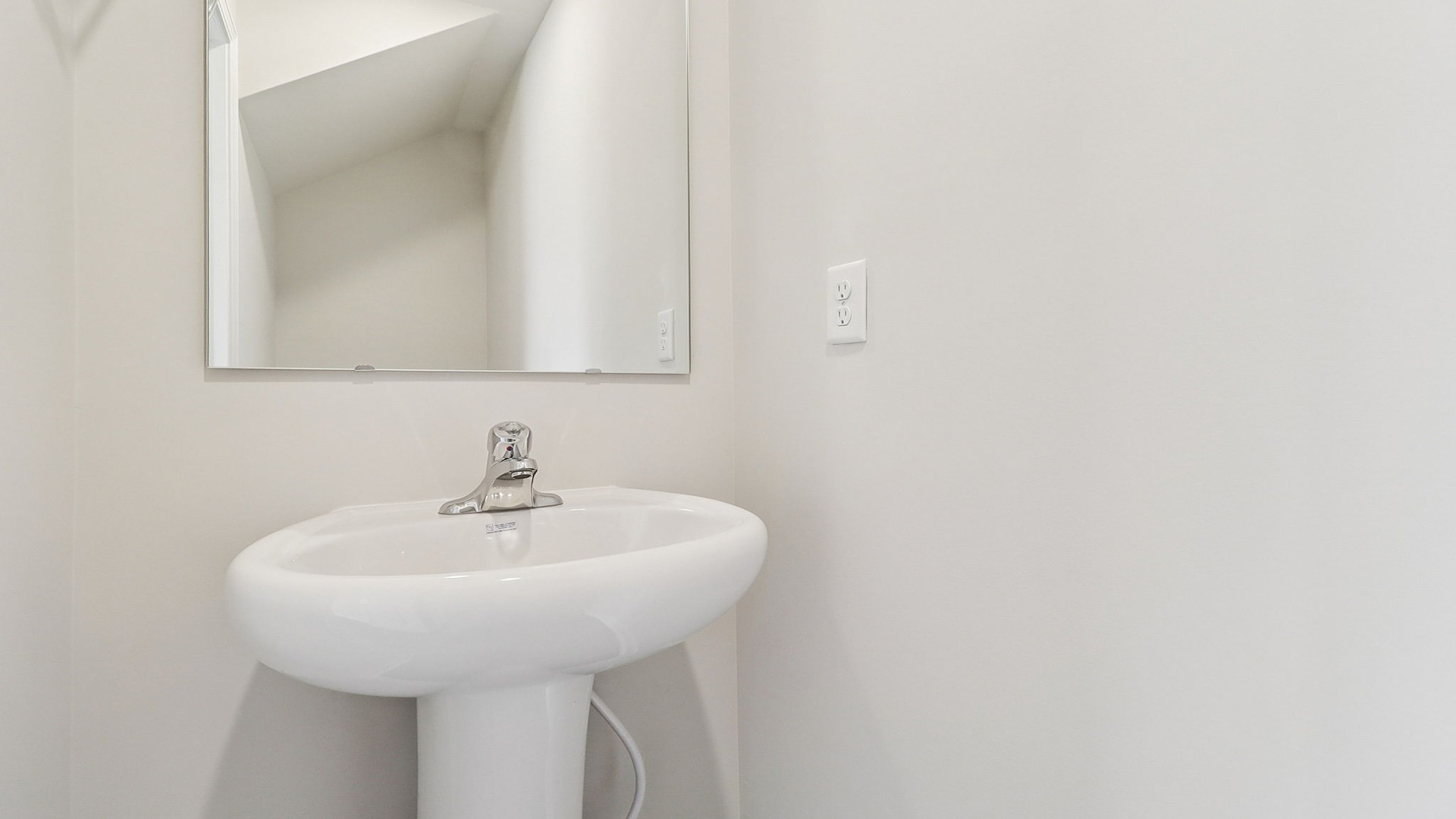 First-floor powder room with pedestal sink and mirror