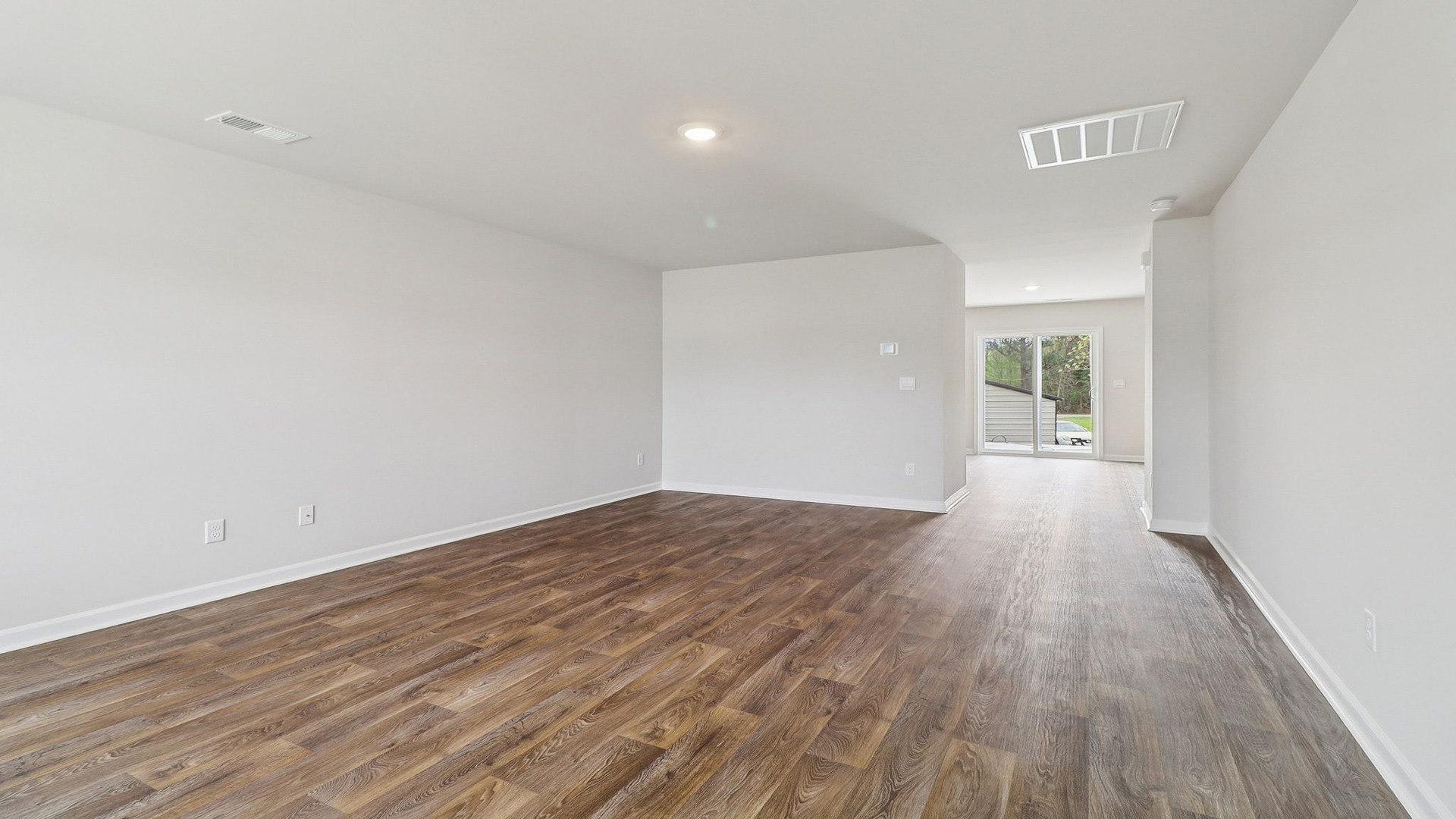 Spacious living area with vinyl flooring that leads into the kitchen and dining areas