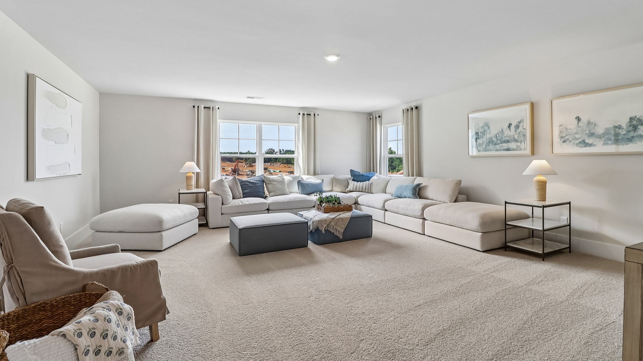 Staged secondary living area in upstairs loft with windows for natural light and carpet floors