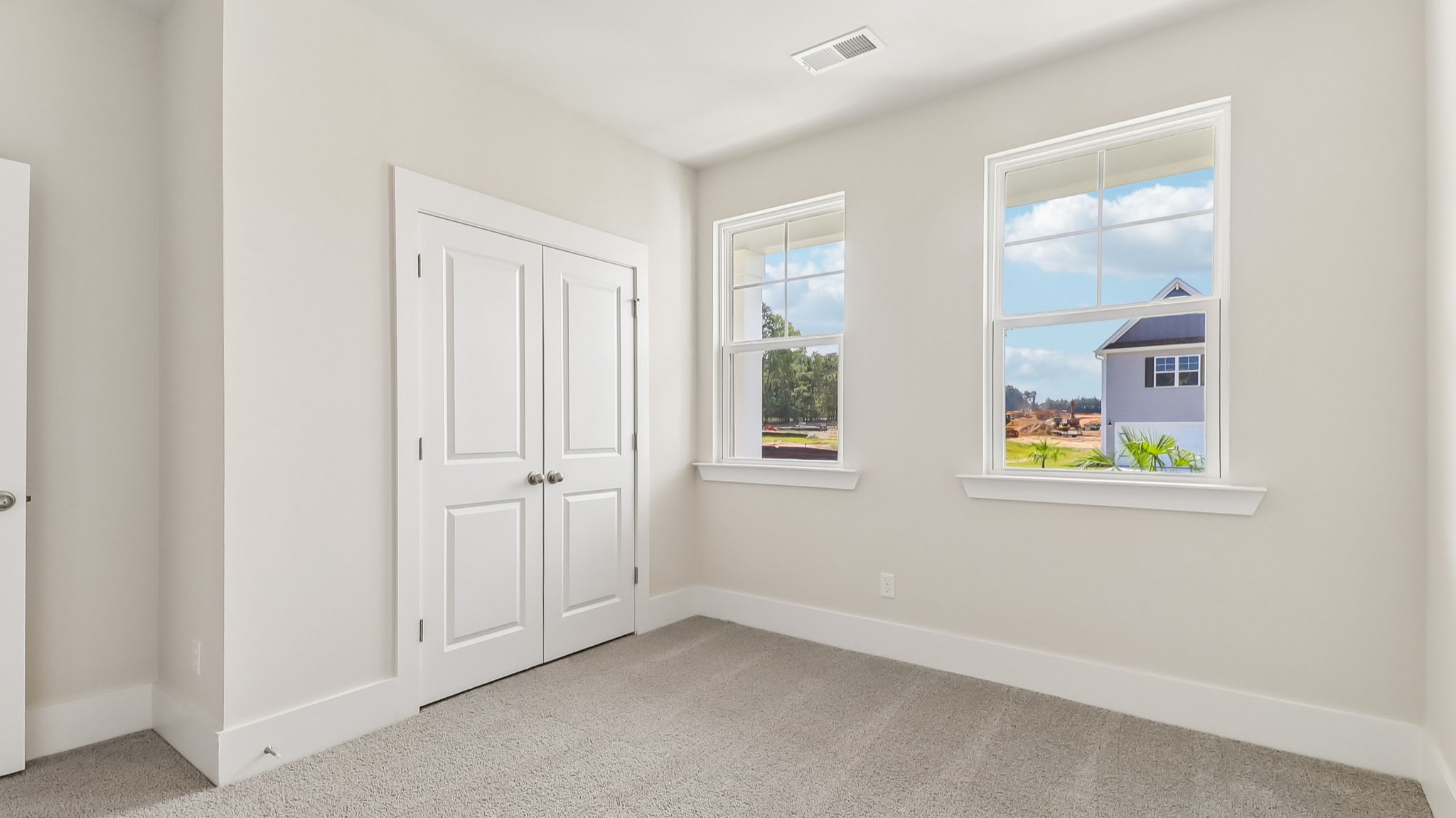 Carpet floors, a private closet, and natural light in front bedroom