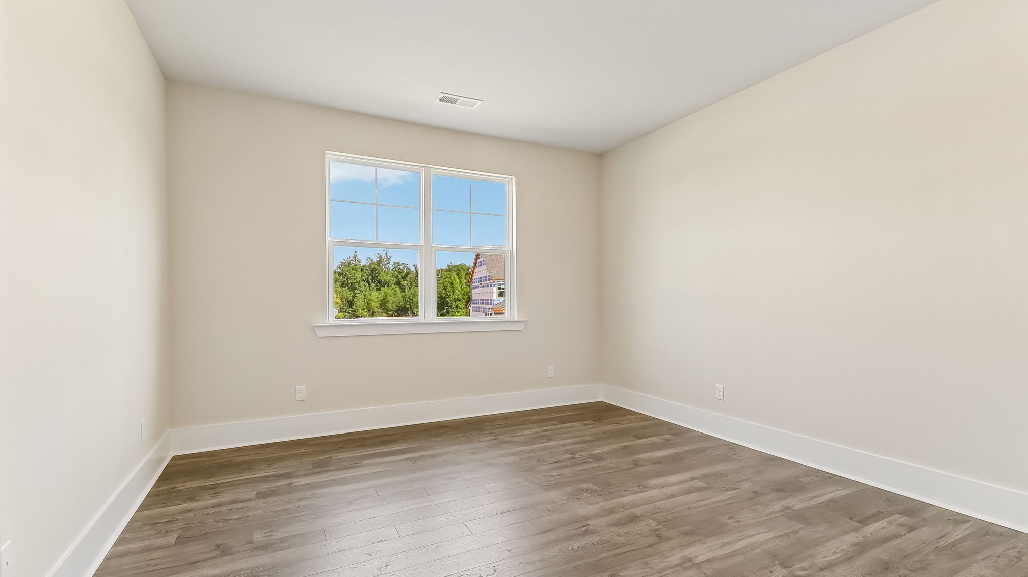 Revwood flooring in the primary bedroom and a window facing the large backyard