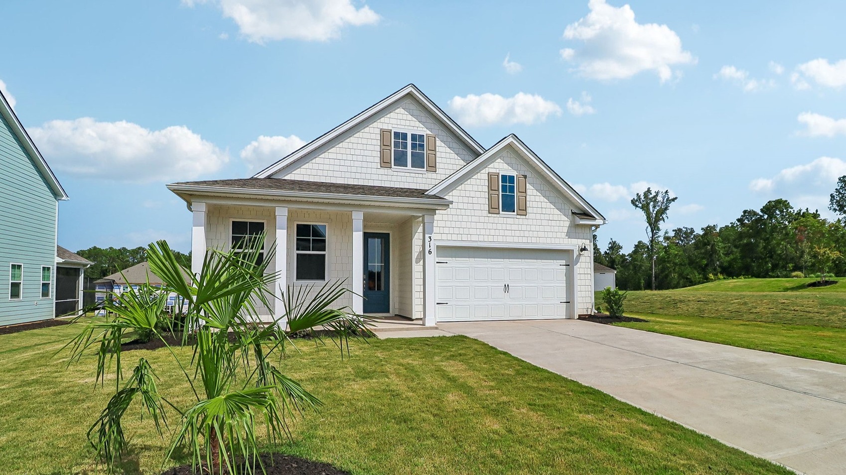 New construction home with sodded yards and a palm tree in the front yard