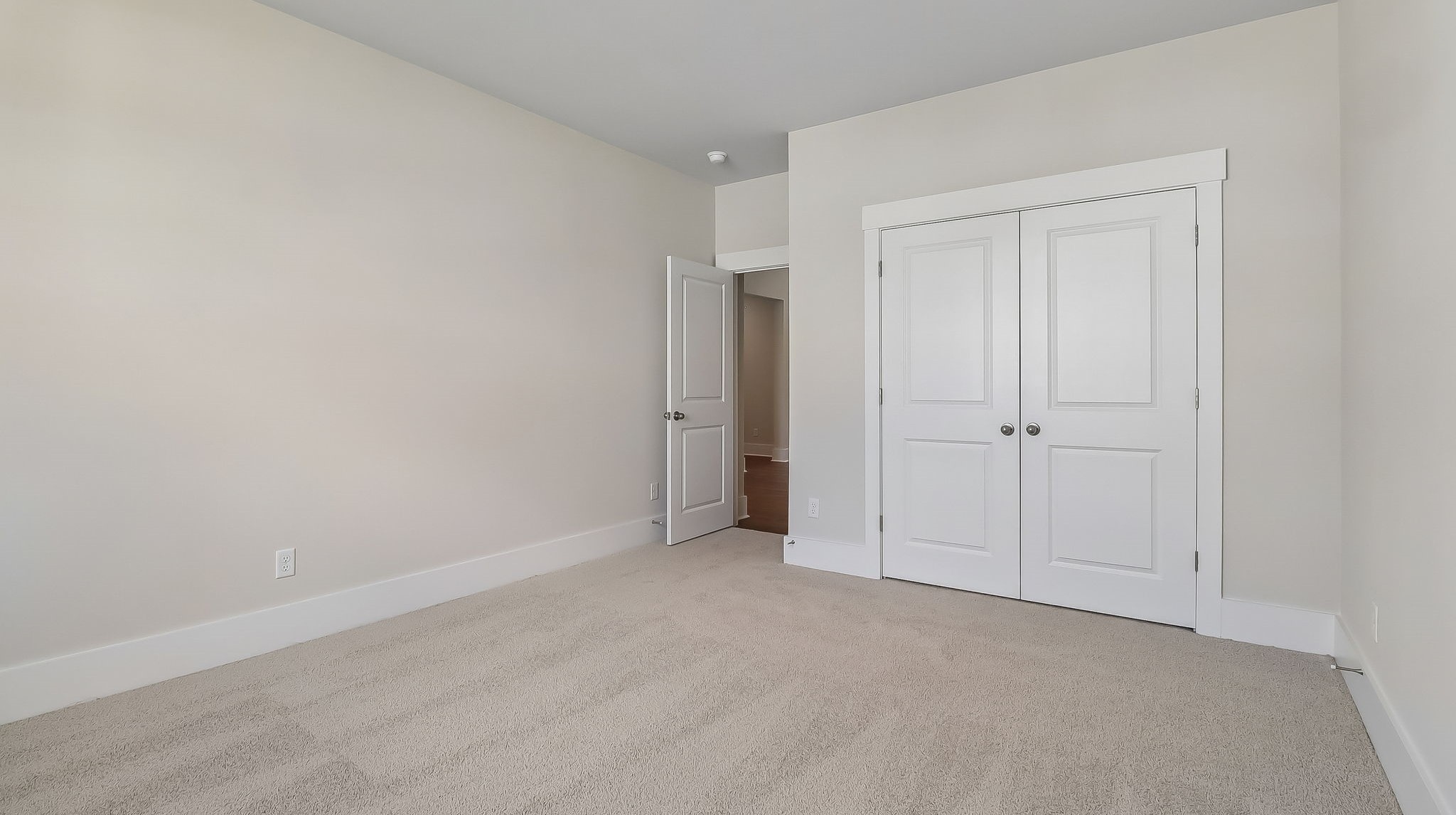 Bedroom 2 with French closet doors and neutral-painted walls