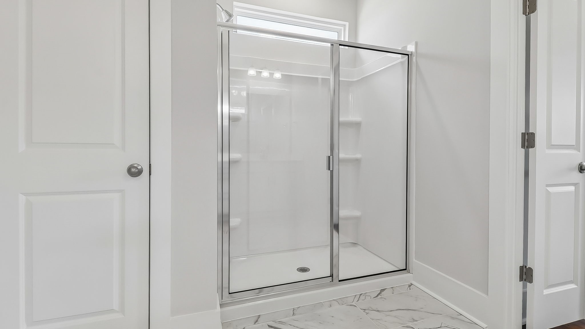 Standup primary shower with glass front and tile bathroom floors