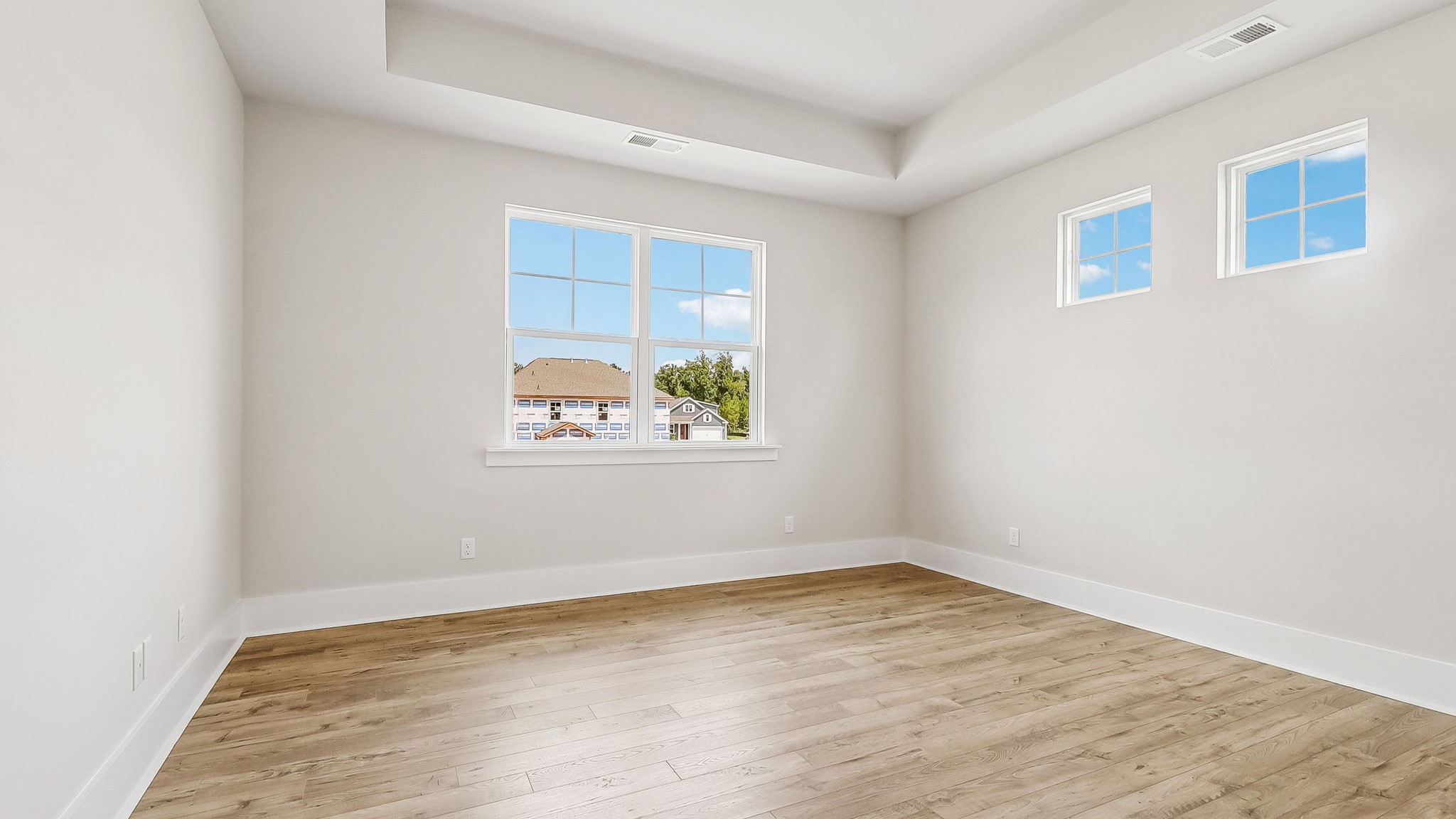 Primary bedroom with a lot of windows for natural light and tray ceiling