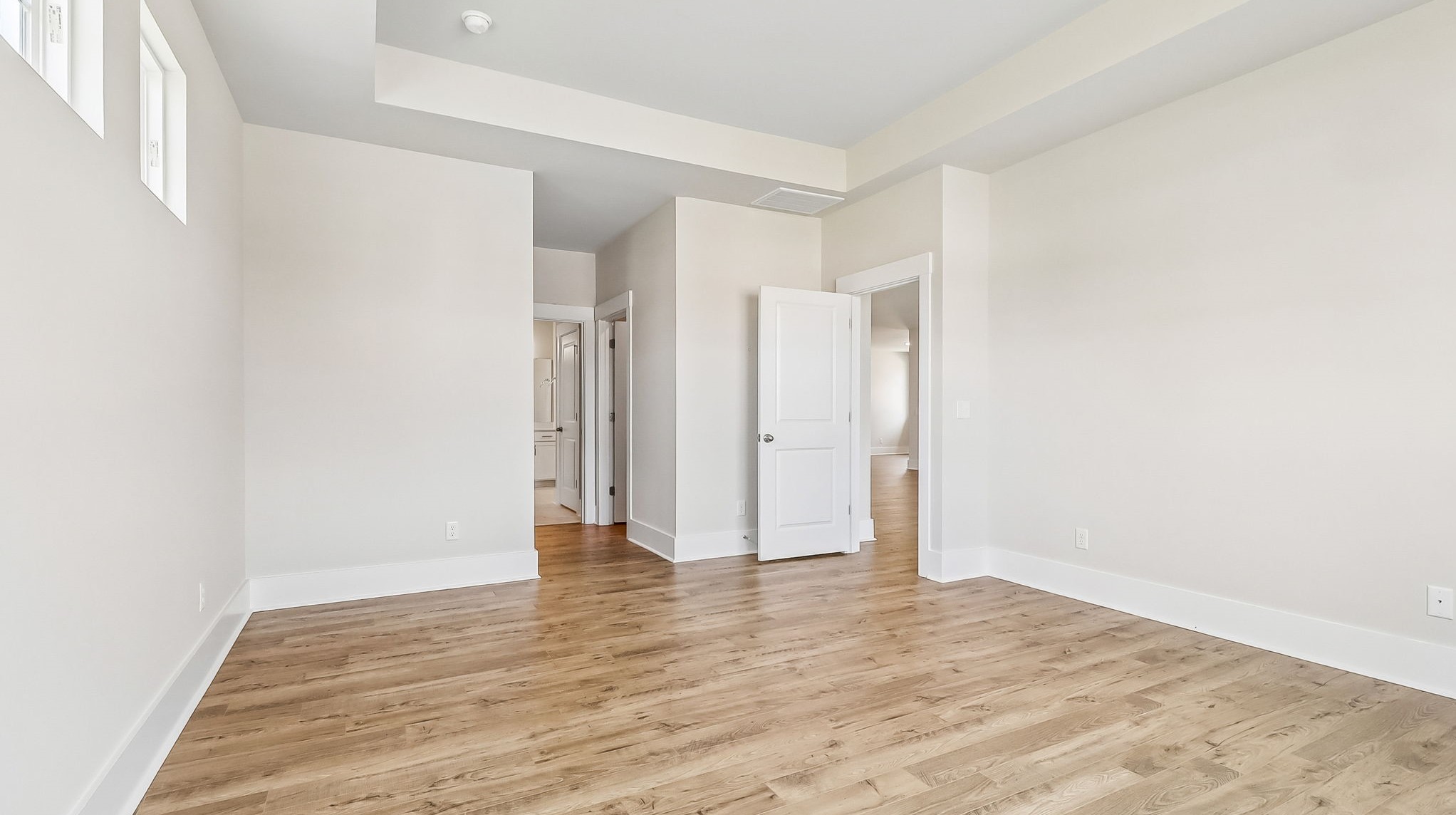 Primary bedroom with durable RevWood floors and direct access to primary bathroom and 2 walk-in closets
