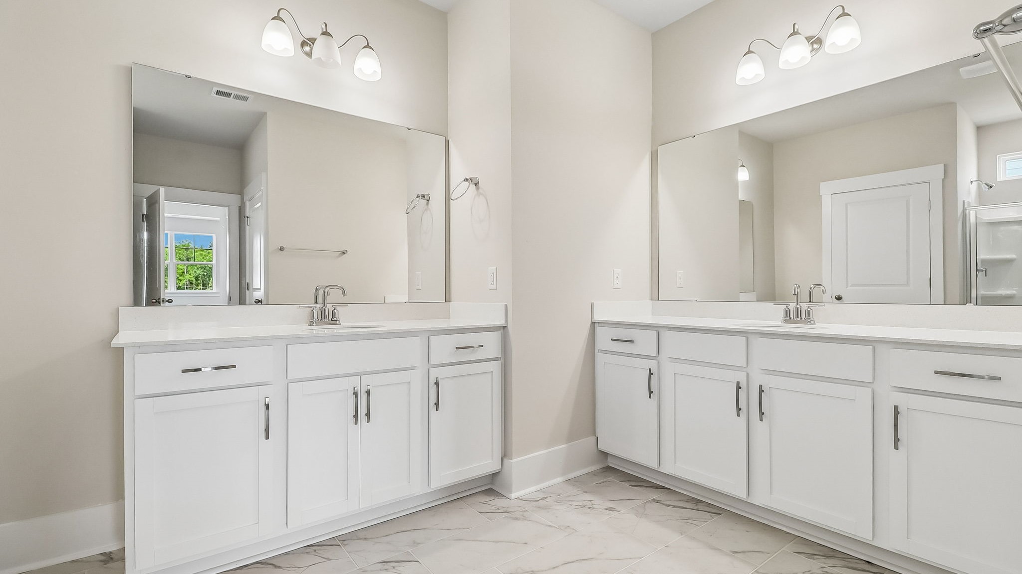 Two vanities in en-suite primary bathroom with white cabinetry and white quartz countertops