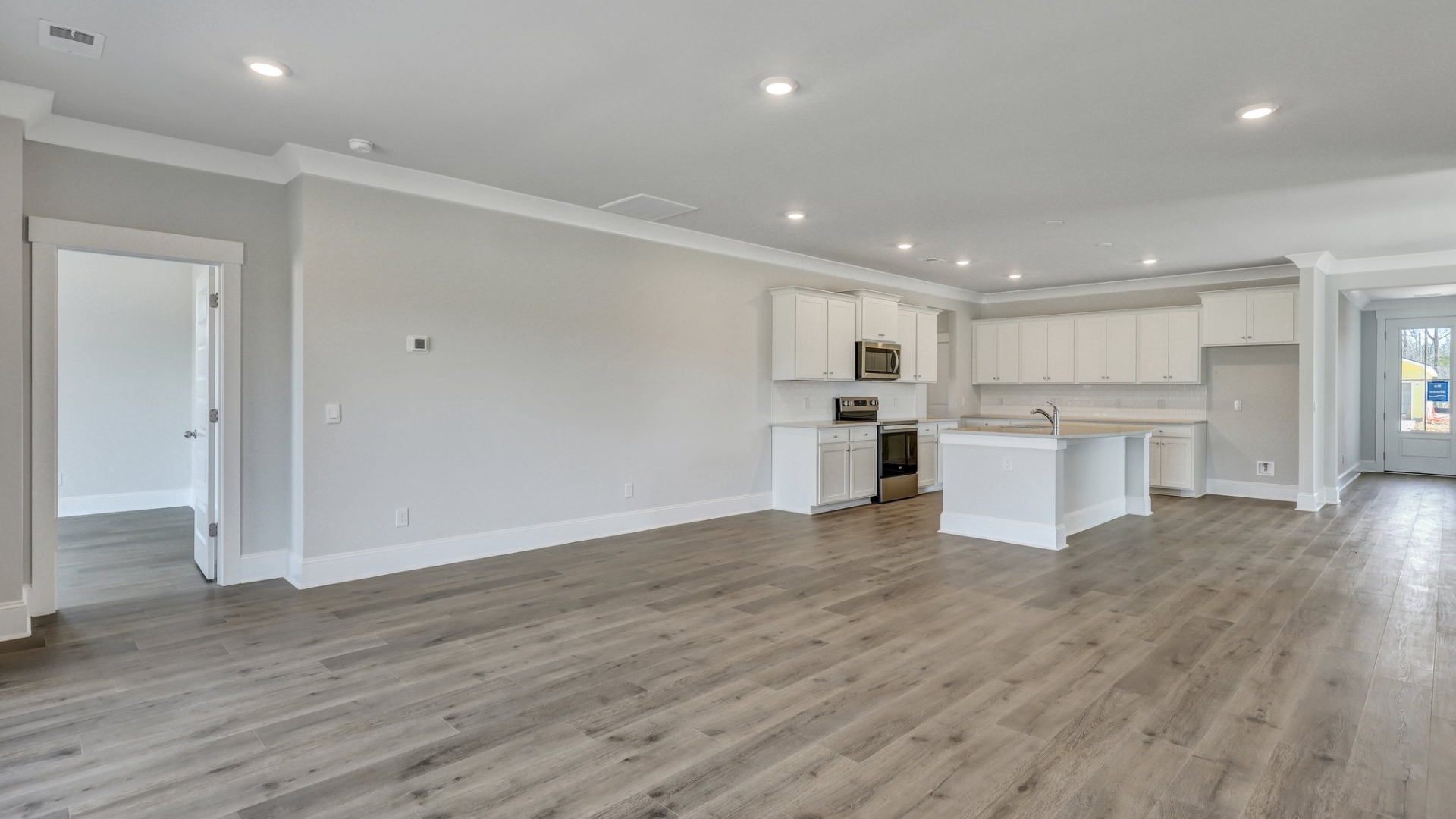 Open living area in new construction home with RevWood flooring and direct access to the kitchen space