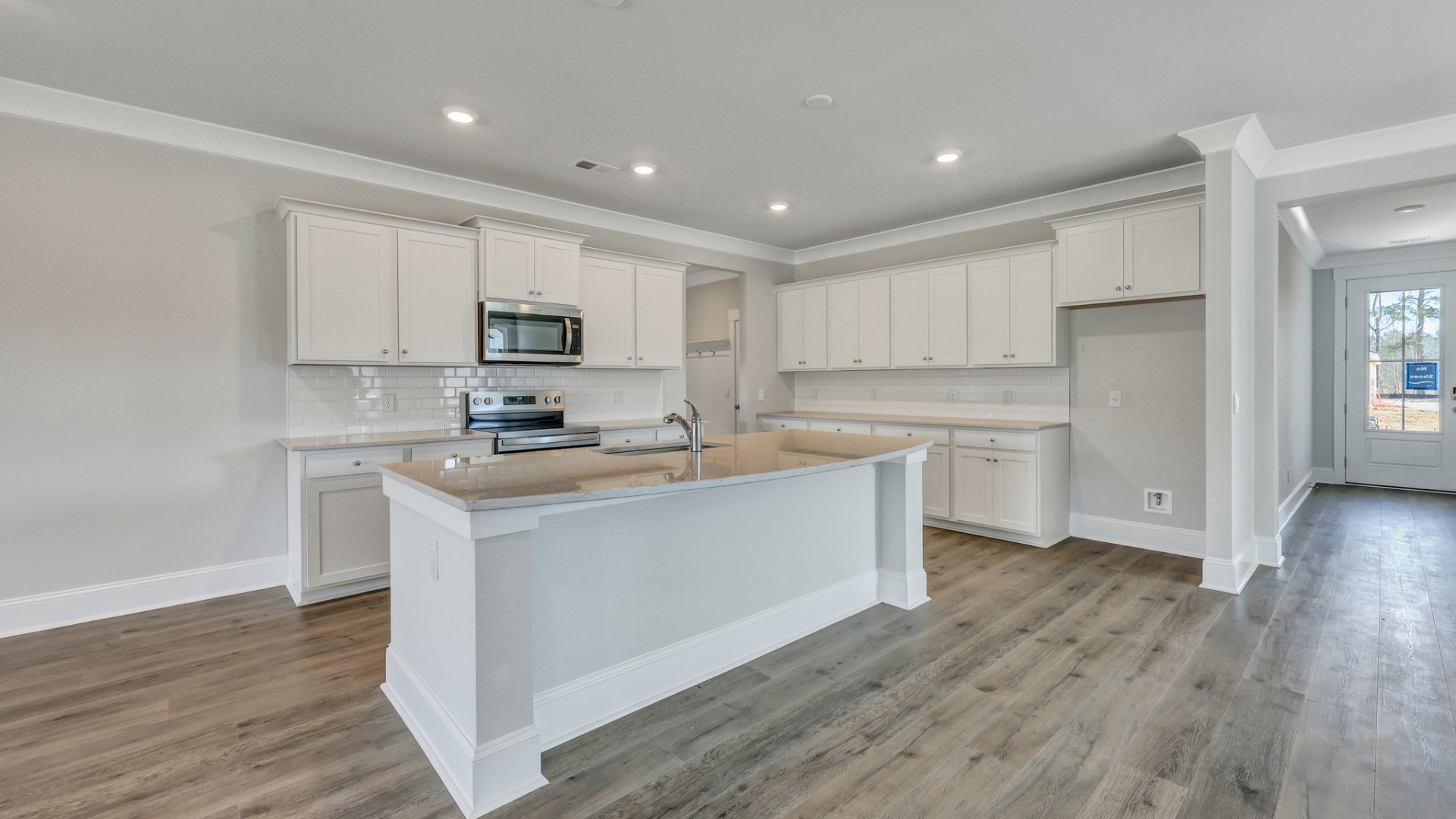 Front foyer opens up into modern kitchen space of new construction home in Shell Pointe
