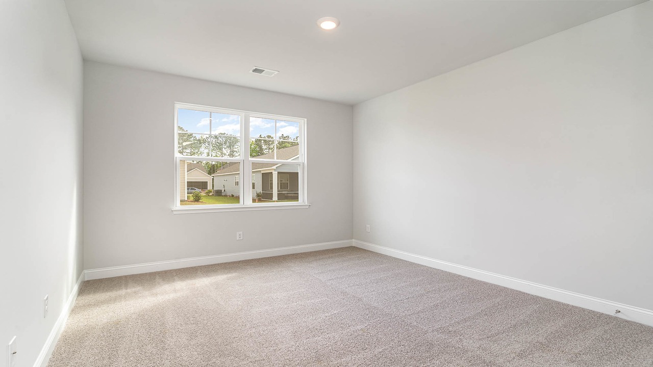 Bedroom 4 downstairs with carpet flooring and a large window facing the backyard