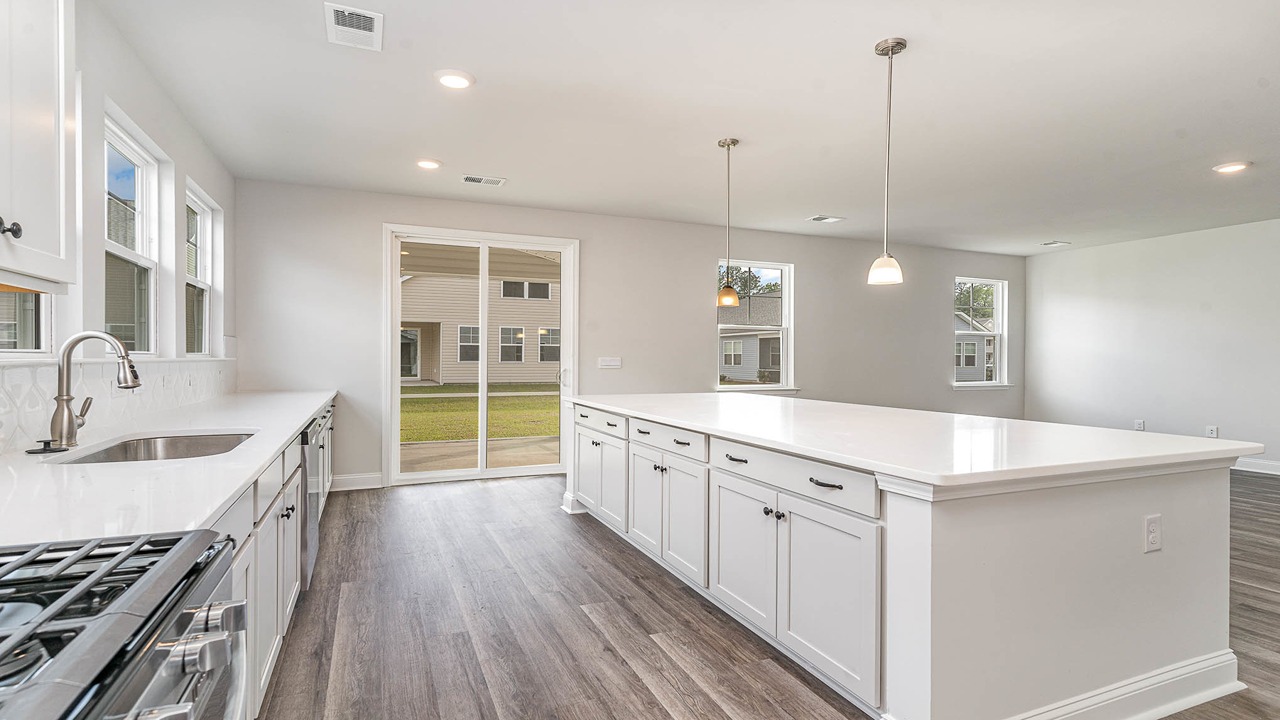 Glass sliding doors in the kitchen space leads to the paved back patio