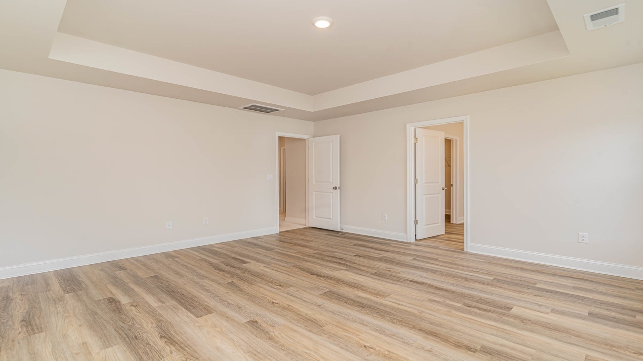 The primary bedroom is spacious with several windows.