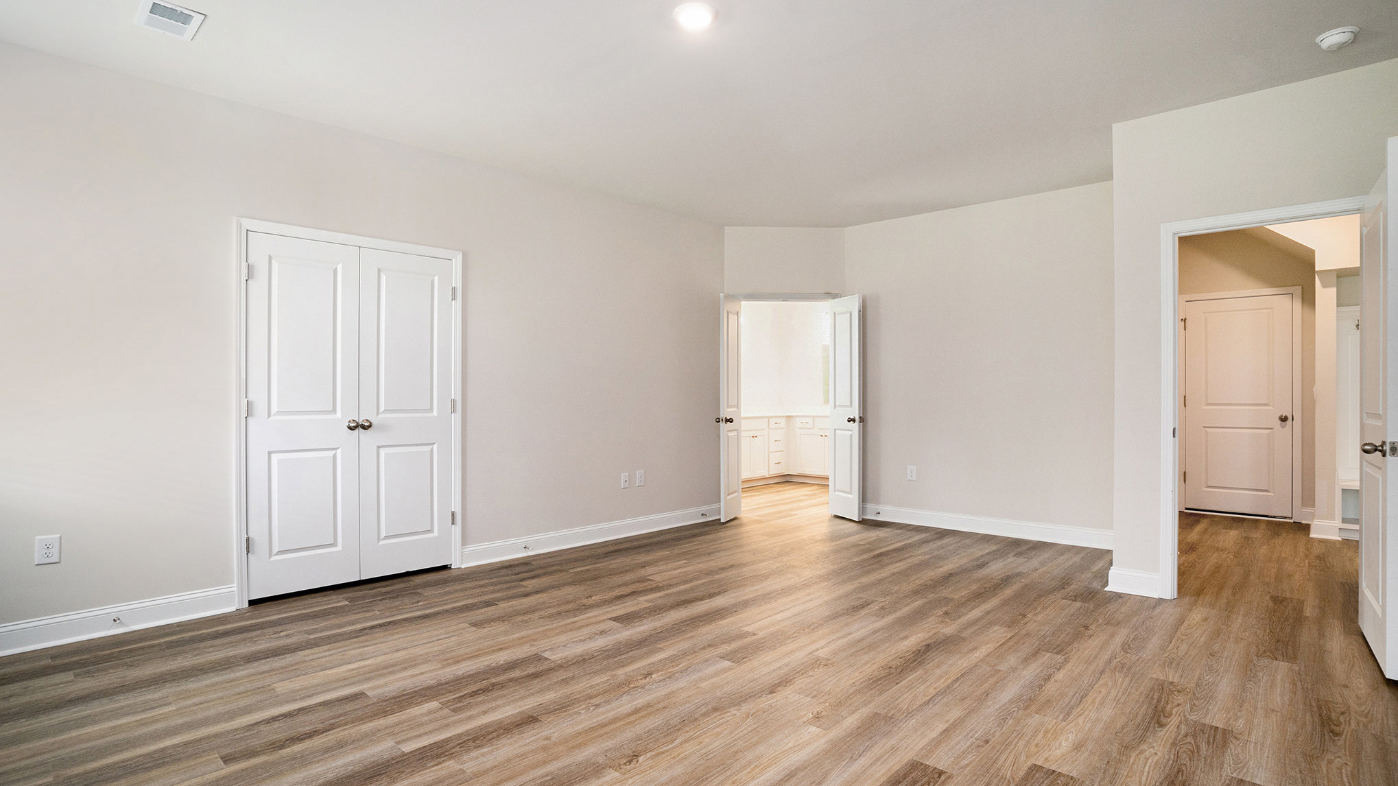 Spacious primary bedroom with access to en-suite closets and bathroom