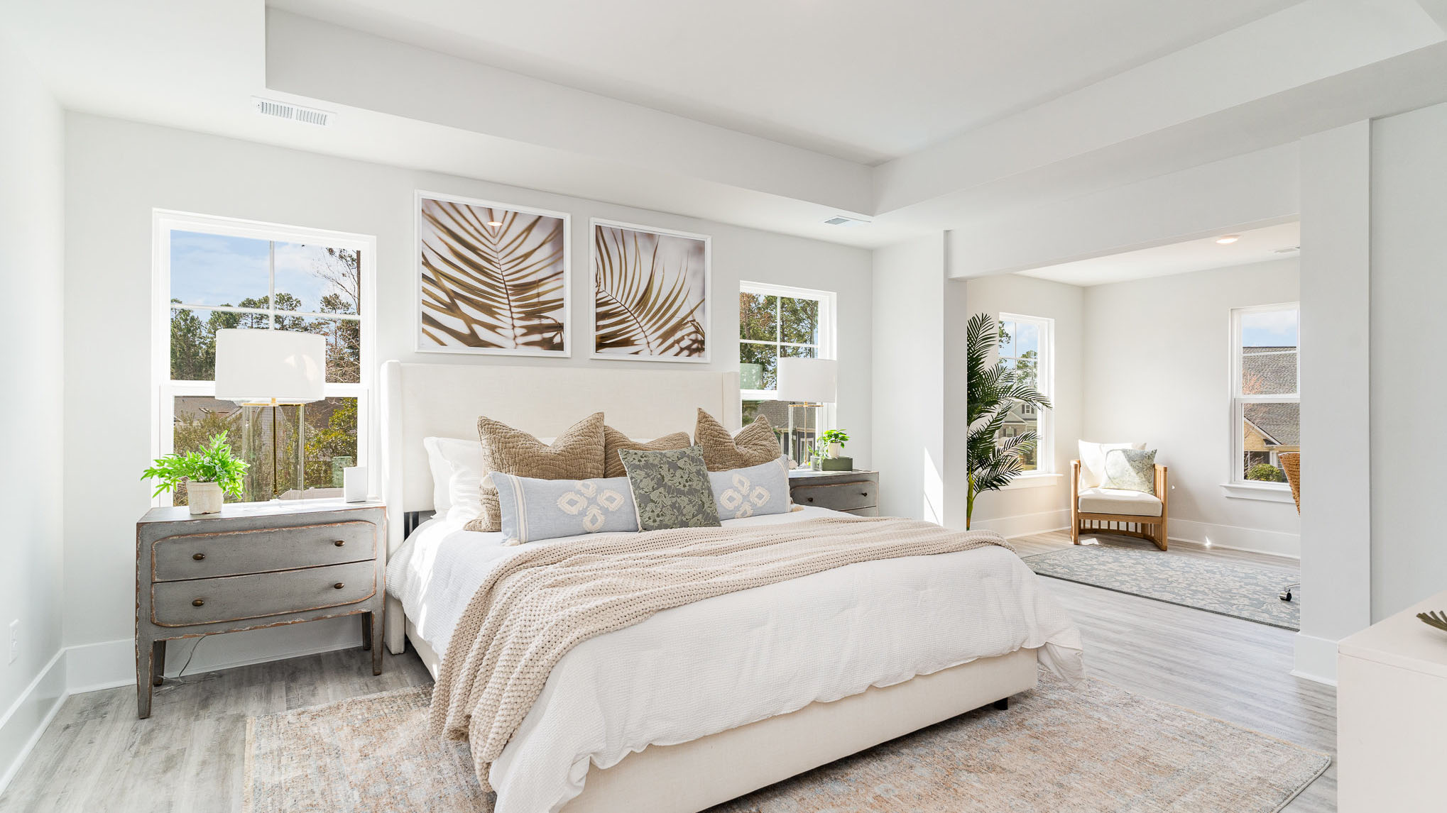 The primary bedroom is spacious with several windows and its own seating room