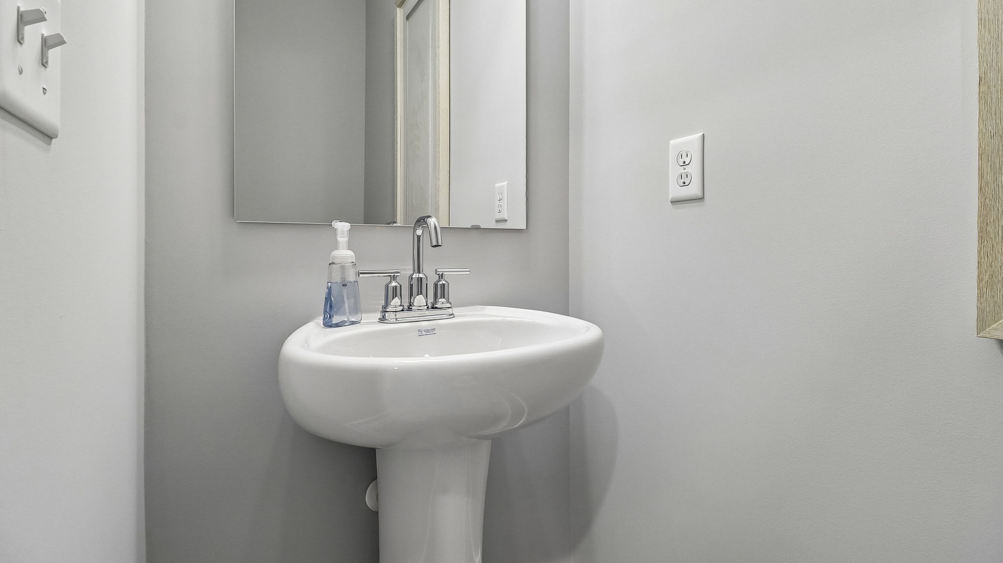 First-floor powder room with pedestal sink and a mirrow