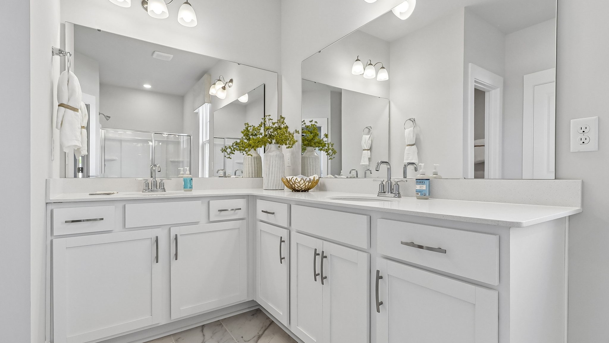 En-suite primary bathroom with dual vanities with quartz countertops