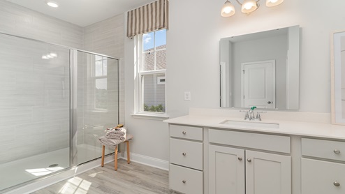 Tillman primary bathroom with double vanities and a standup shower
