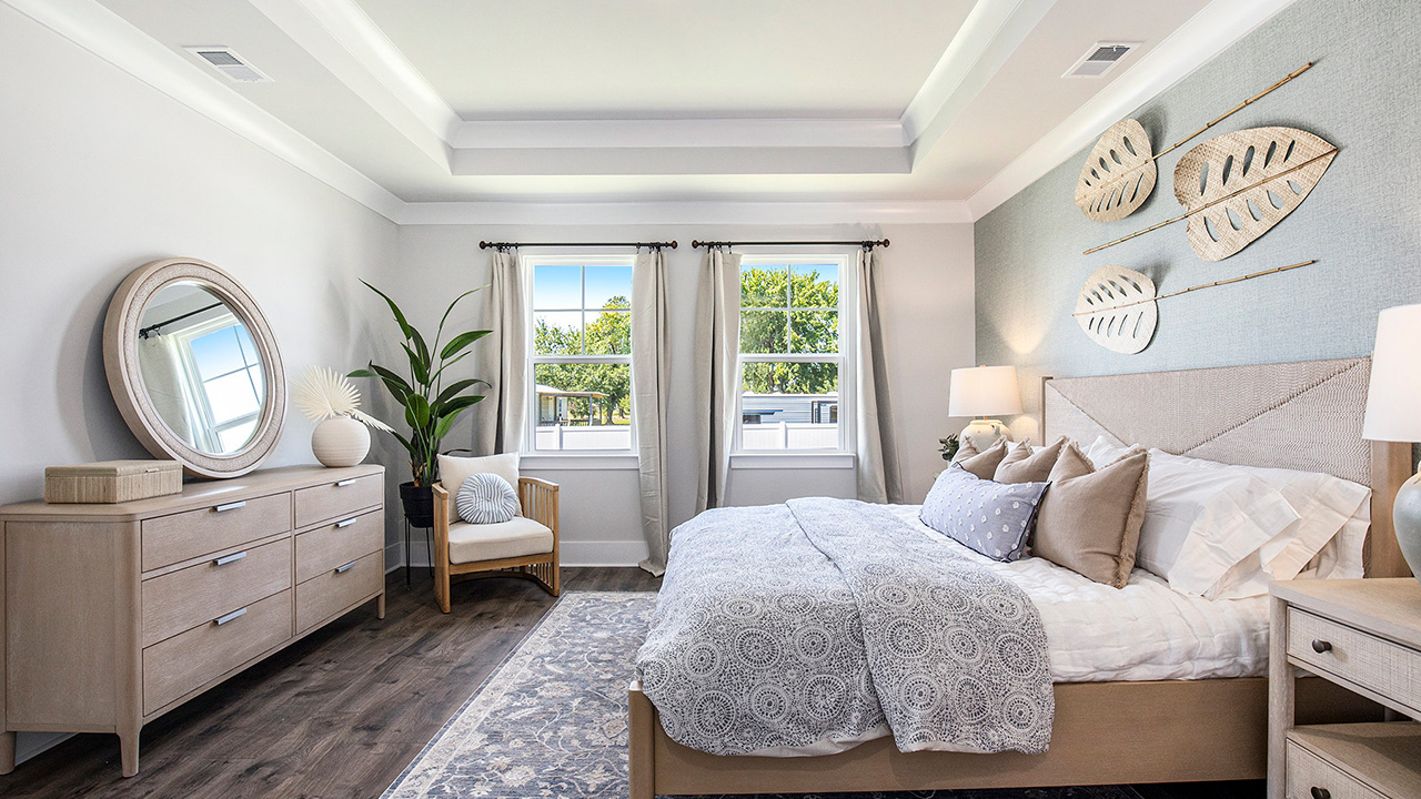 Primary bedroom with tray ceilings and RevWood flooring