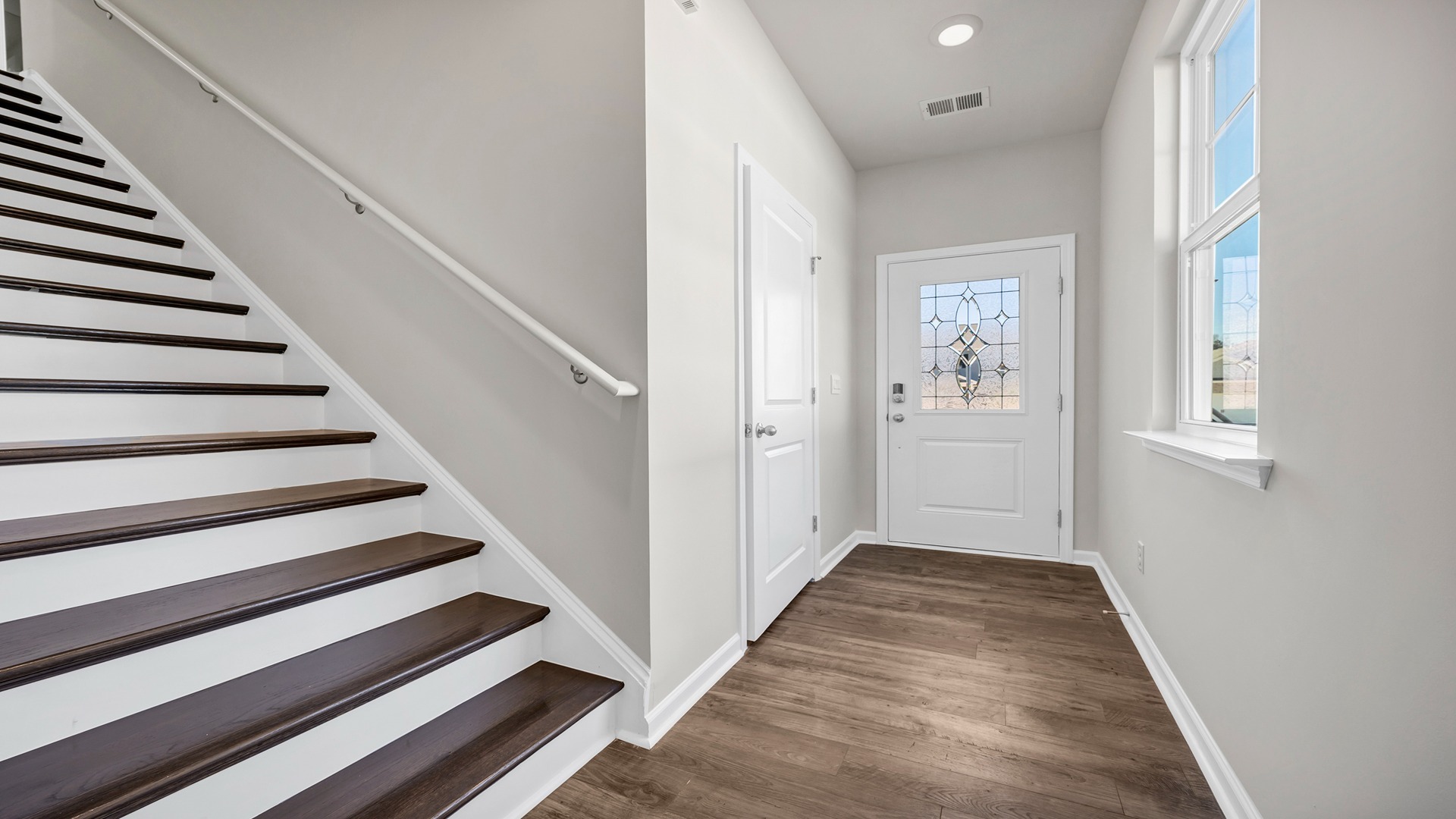 Entry way with many windows and natural lighting leading to the stairs and main living areas.