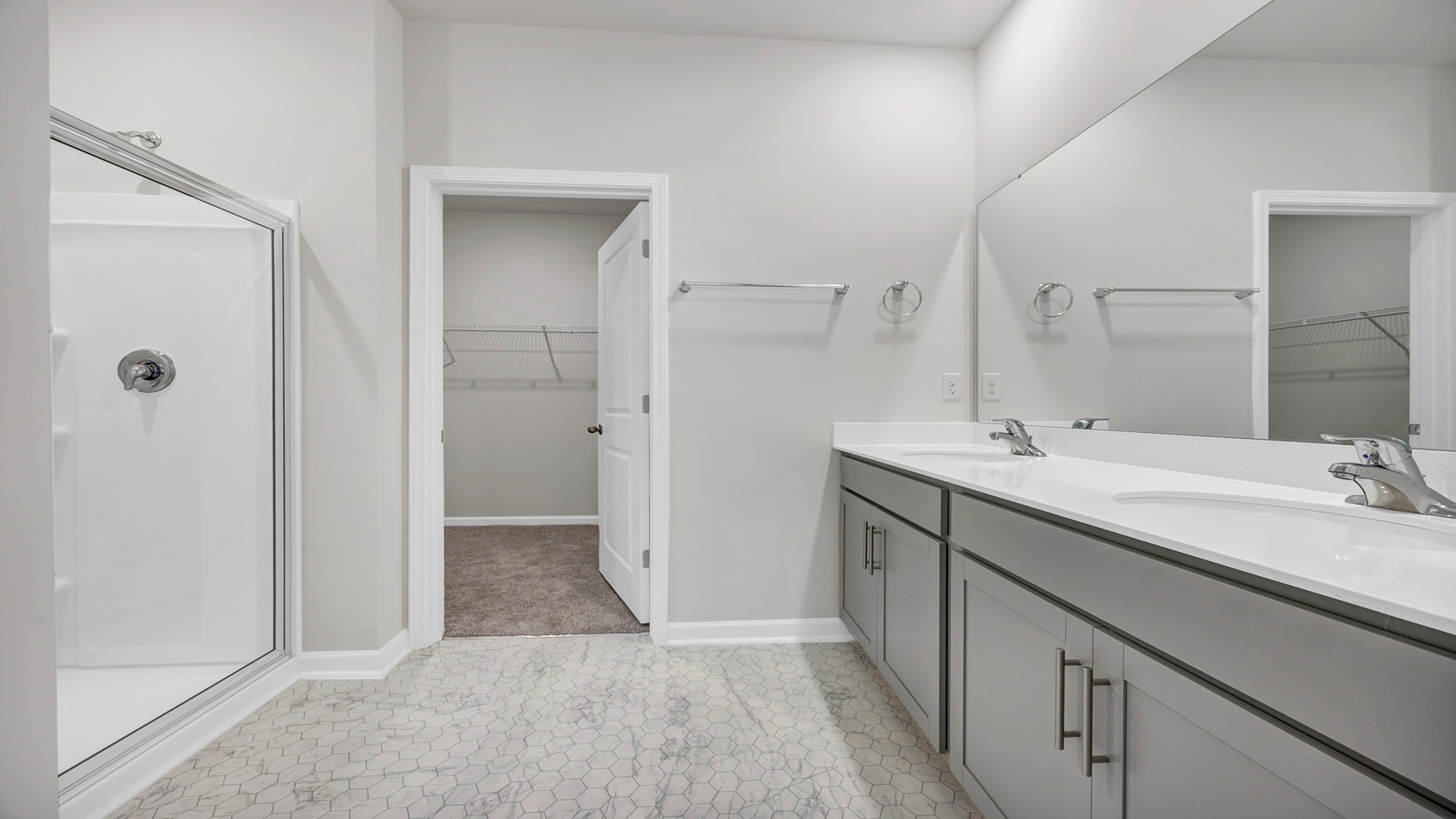 There are double sinks and grey cabinetry in the primary bathroom.