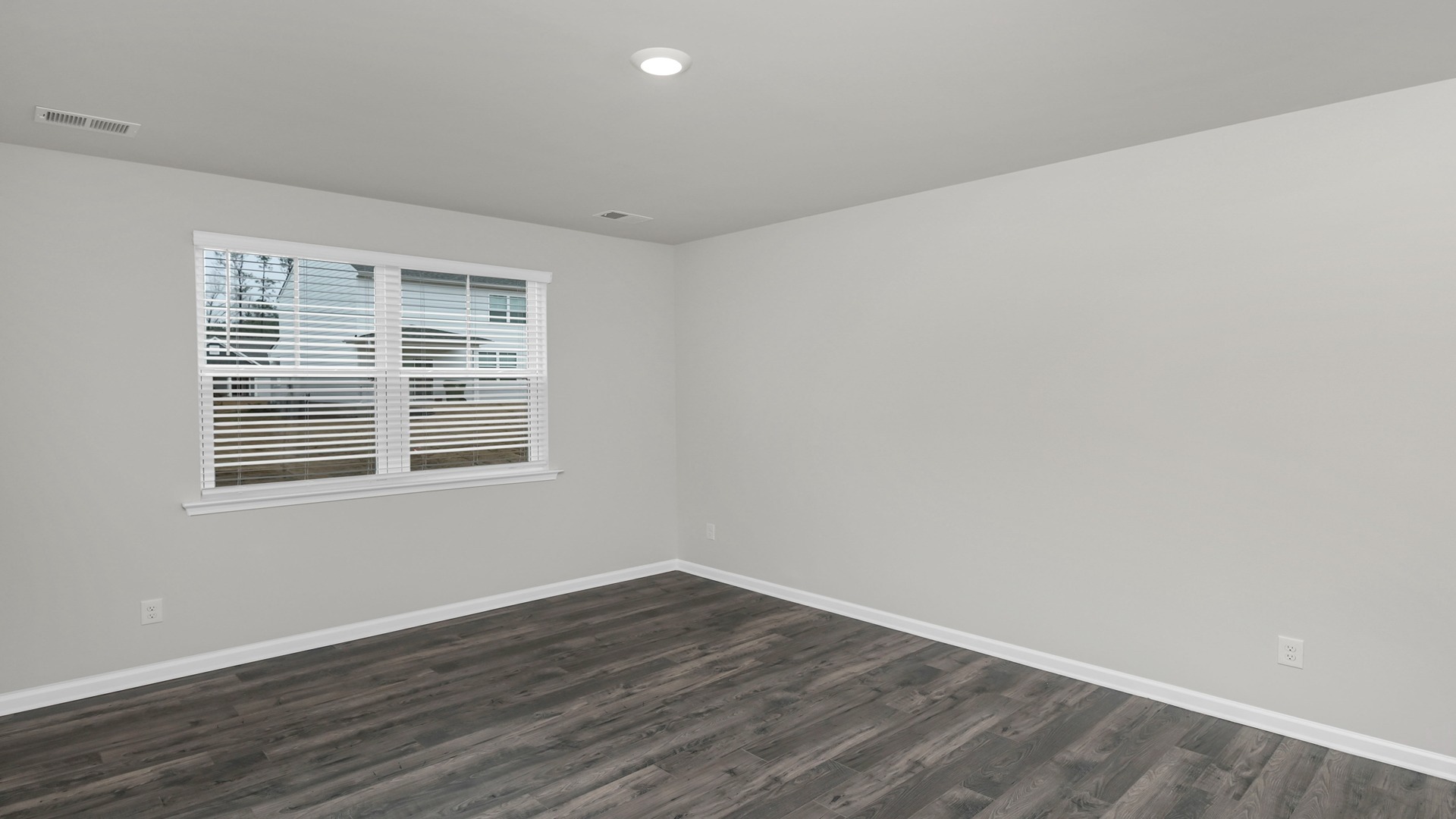 Primary bedroom downstairs with Revwood flooring and a large window for light