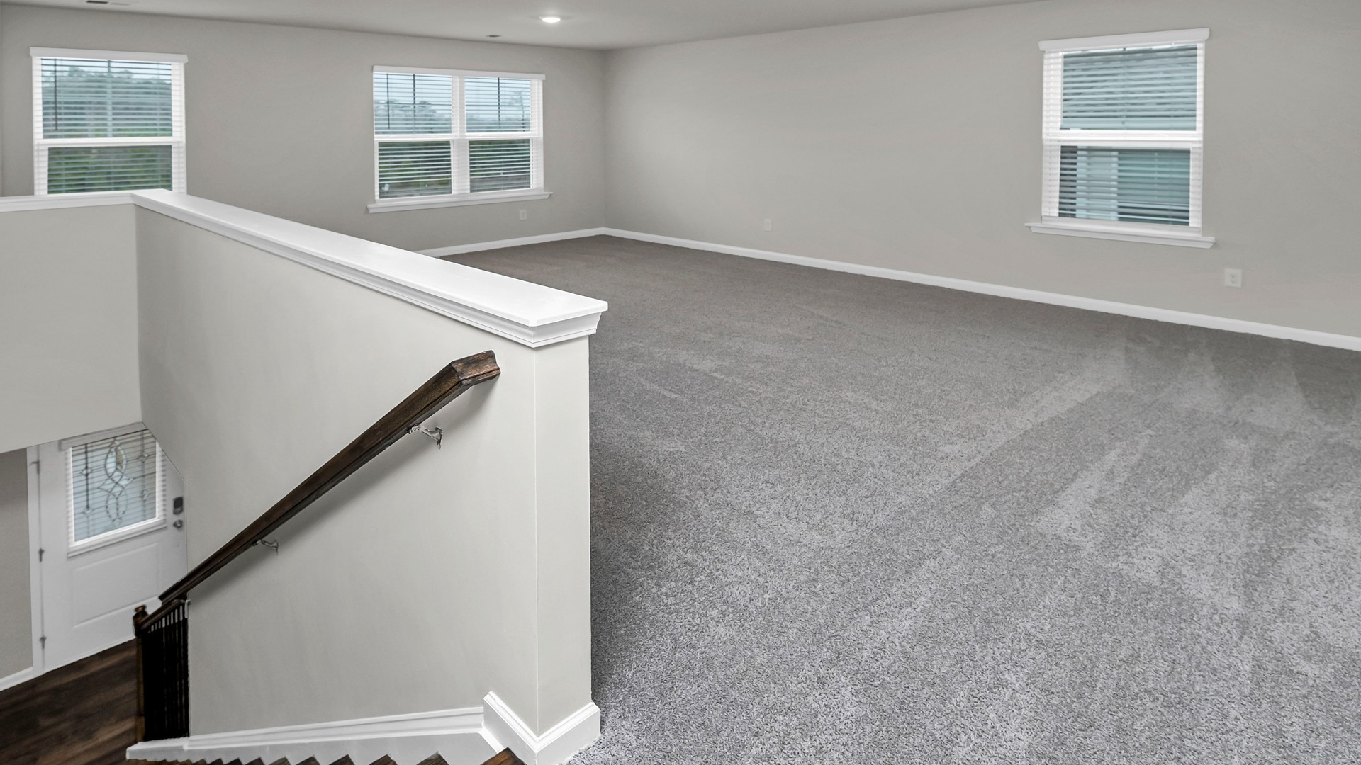 Upstairs large functional loft space with carpet flooring and several windows