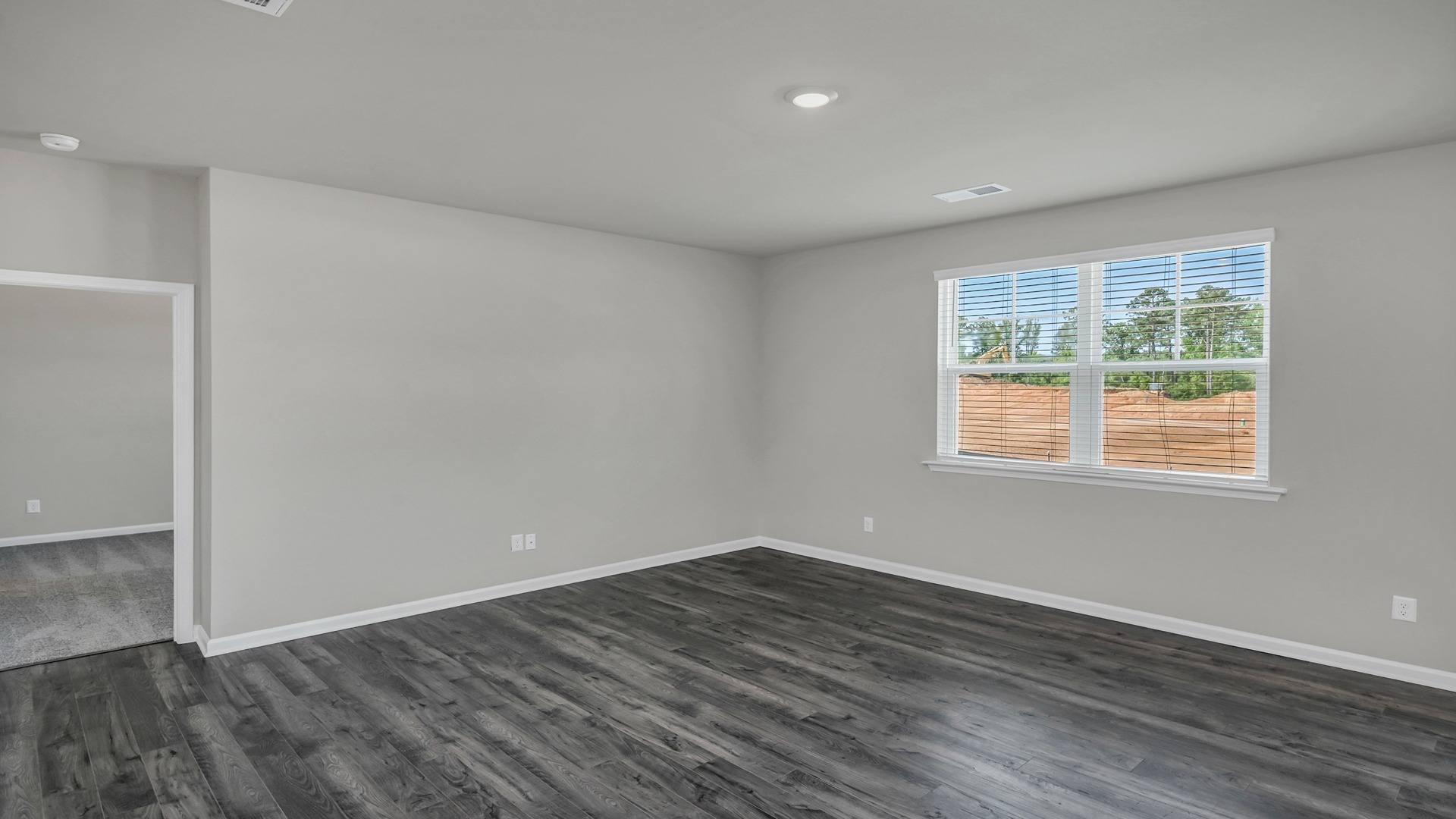 Living area on first floor of new construction home with access to private primary suite