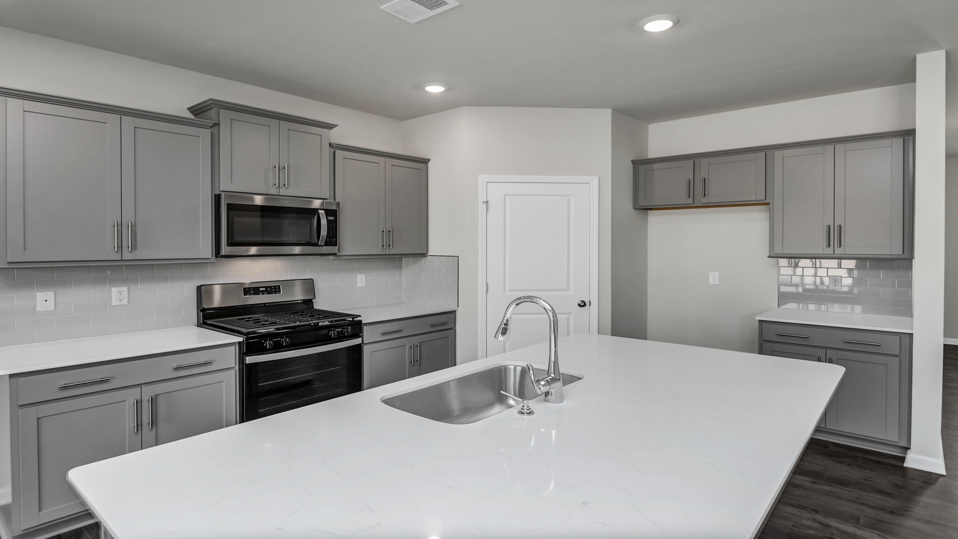 Sleek, white quartz countertops in the kitchen space of new construction home for sale in Blythewood