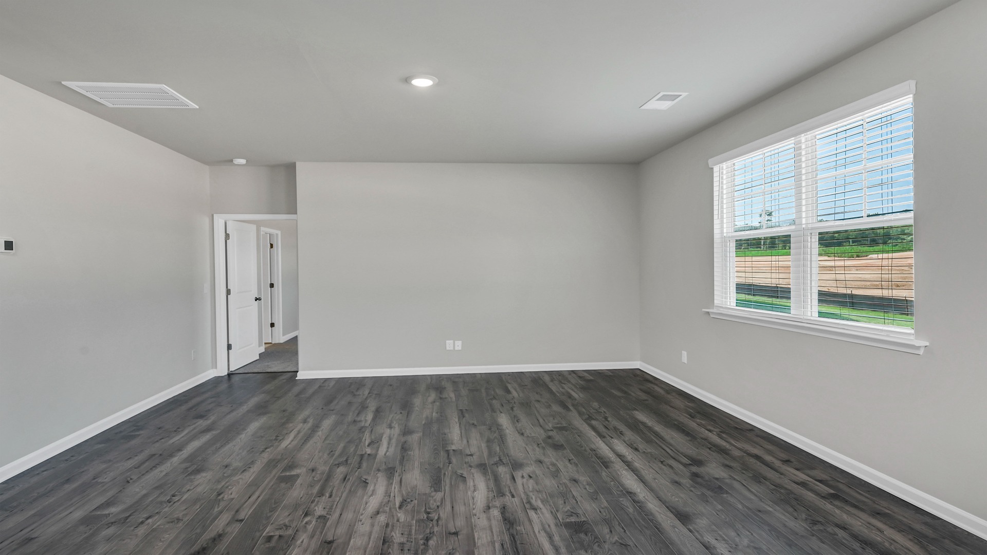 Living space with RevWood floors and a window for natural light overlooking the spacious backyard