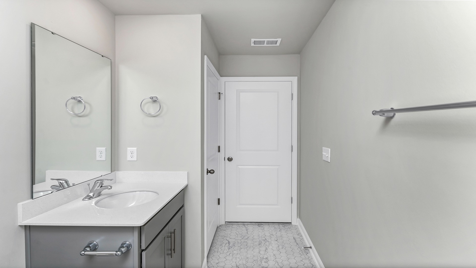 Bathroom vanities have white quartz countertops and gray cabinets below