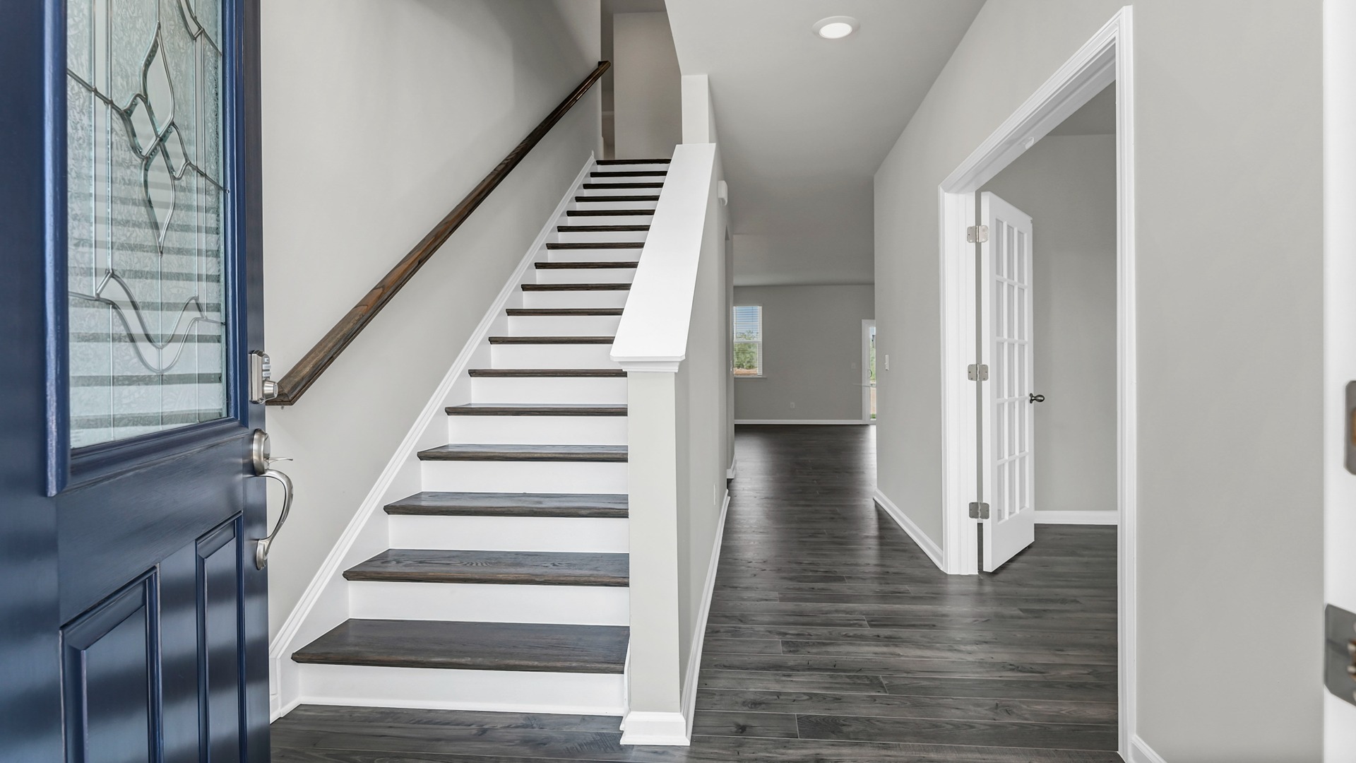 The navy-blue front door opens into the front foyer of new construction home
