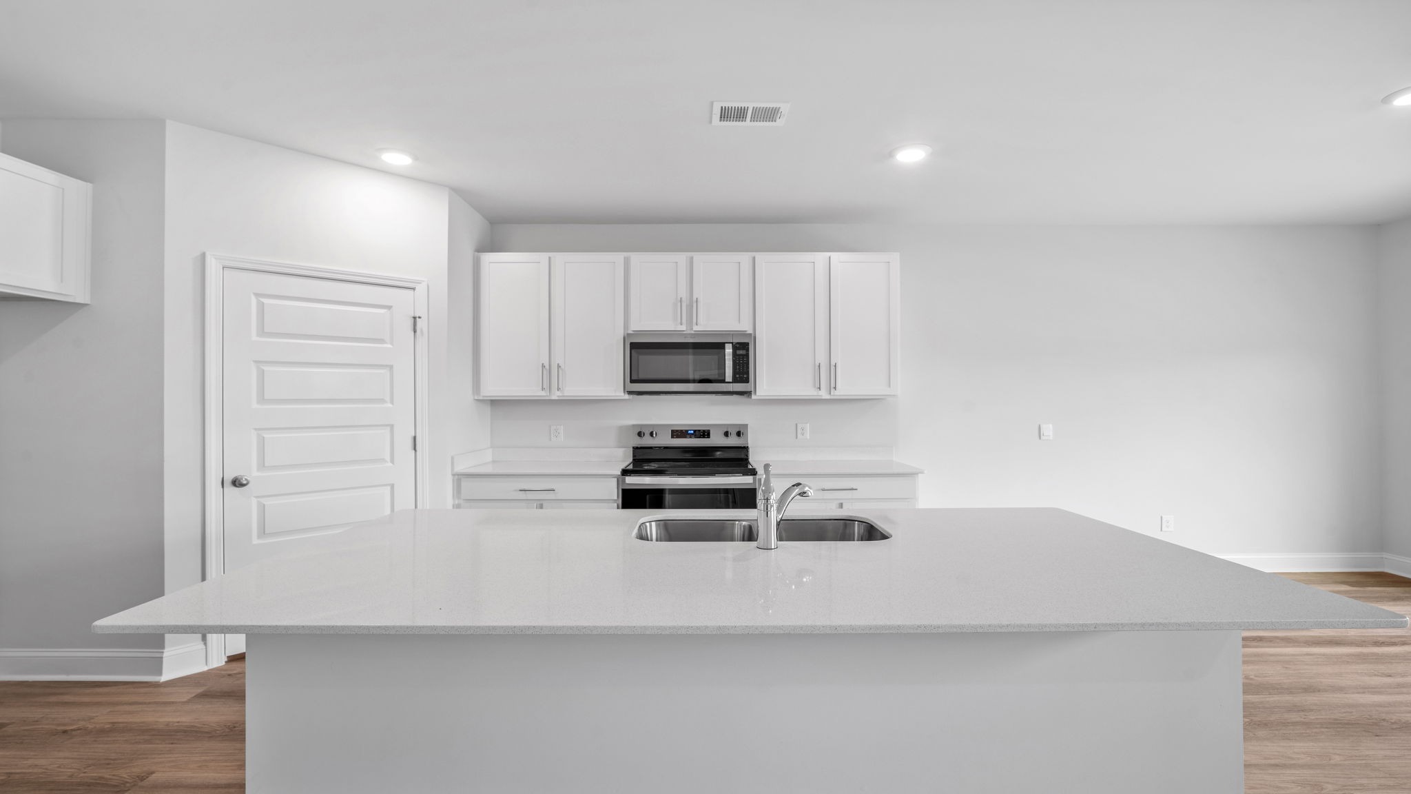 Elle kitchen with white cabinets and white quartz countertops.