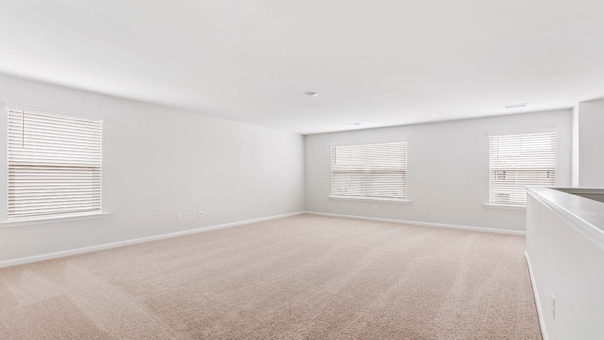 Large upstairs living area with several windows at the top of the stairs.