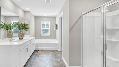 There are double sinks and white cabinetry in the primary bathroom.