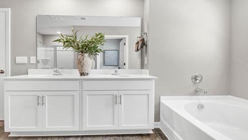 There are double sinks and white cabinetry in the primary bathroom.