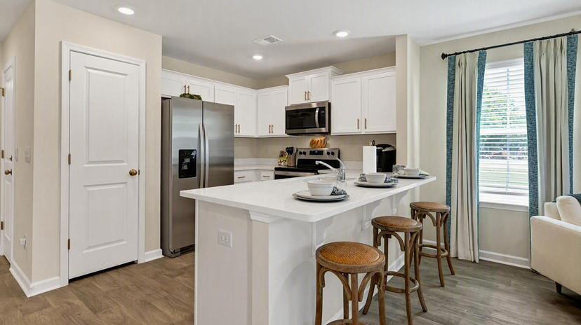 Quartz countertops, white cabinets, and a bar overlooking living area in the Pearson kitchen