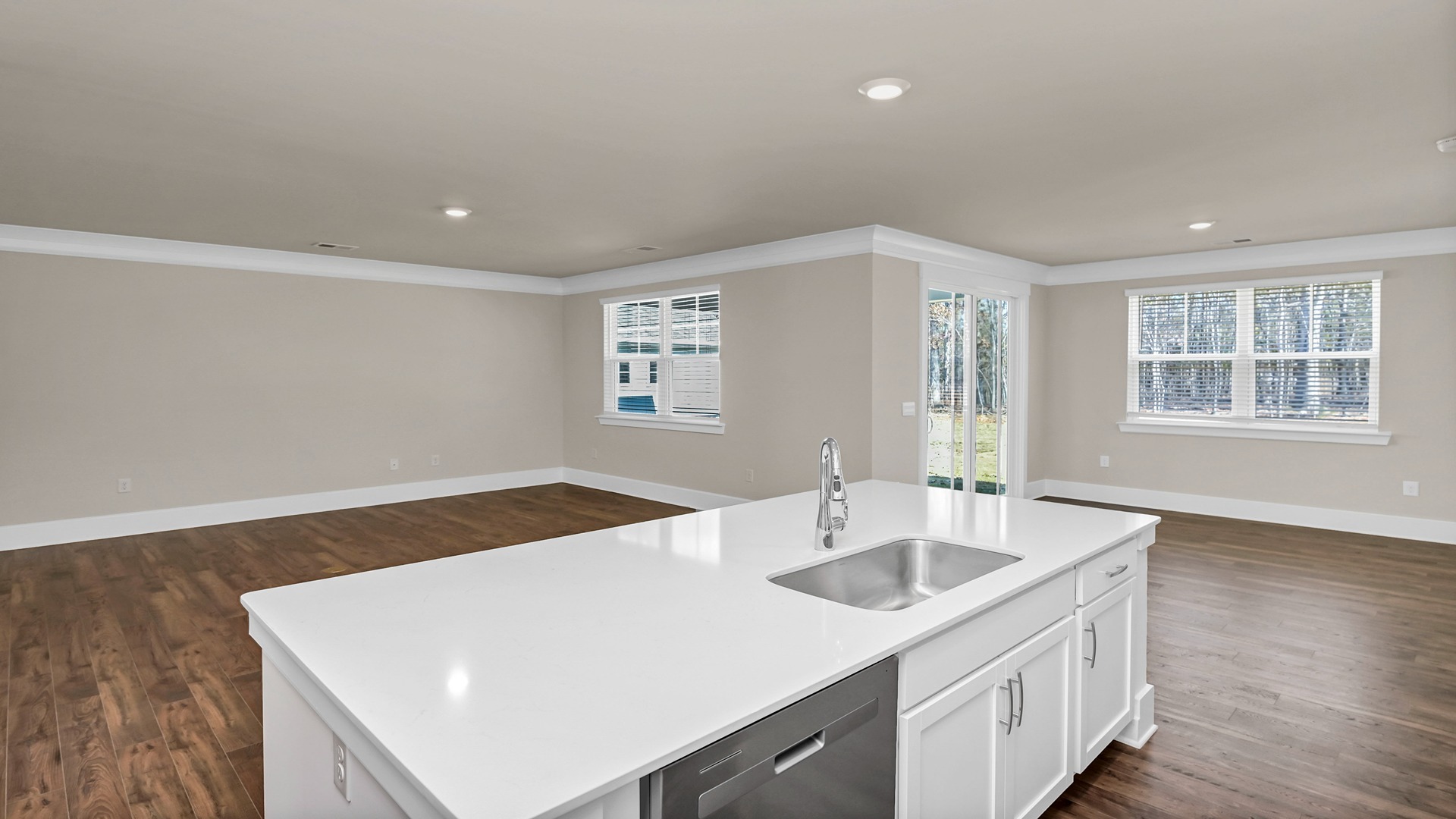 Floating kitchen island with sink overlooking the open main living areas in new home for sale