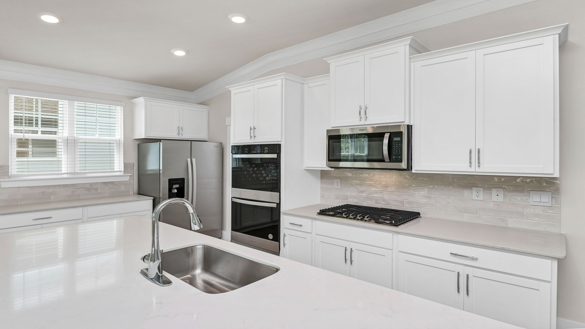 White quartz countertops and modern tile backsplash in the kitchen of new construction home for sale